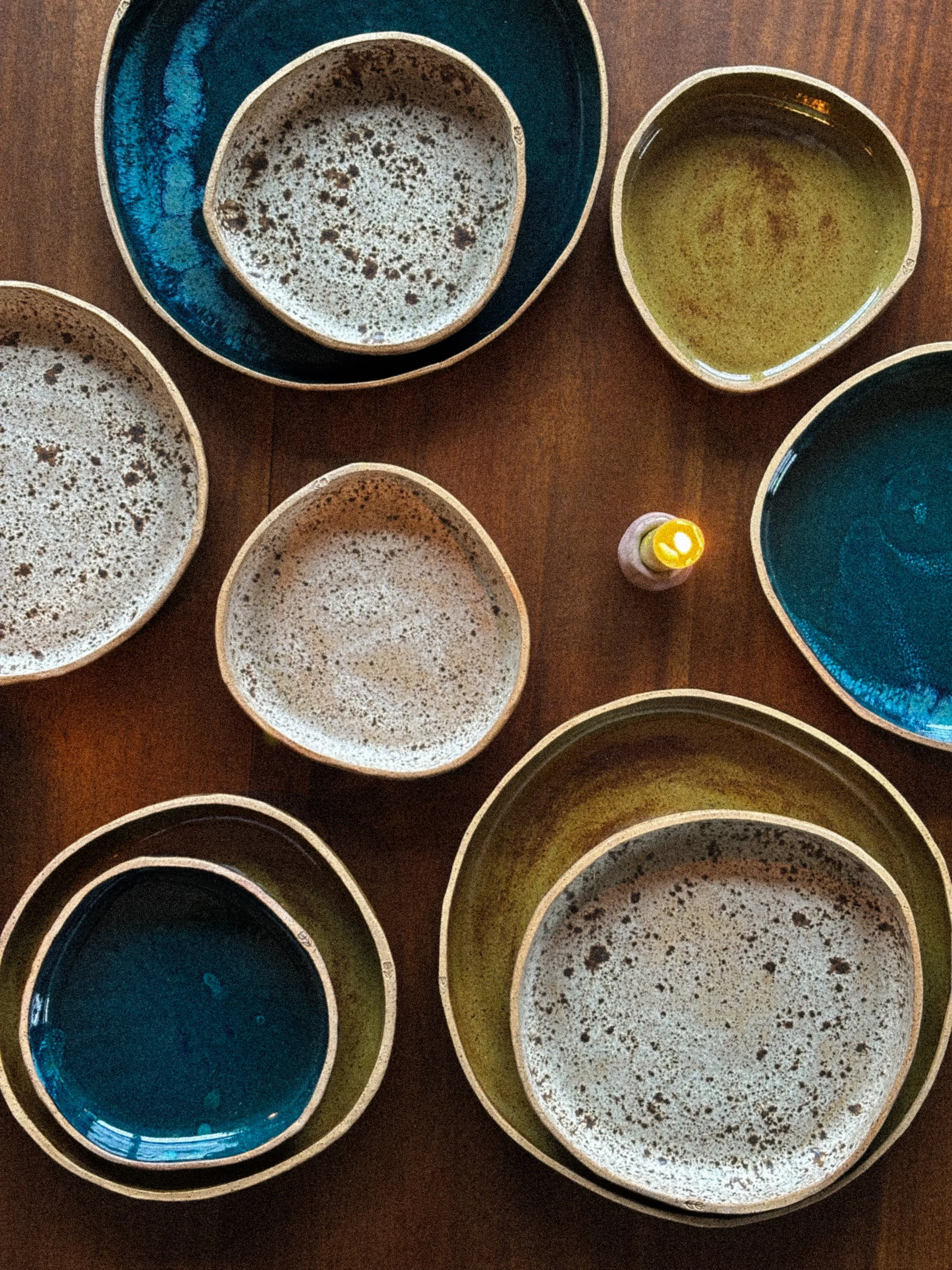 Multiple empty ceramic bowls on a wooden table, with one small bottle of oil or seasoning in the center.