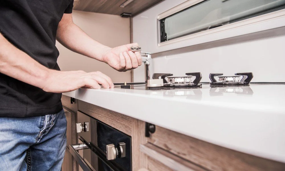 Person fixing a stove in a kitchen.