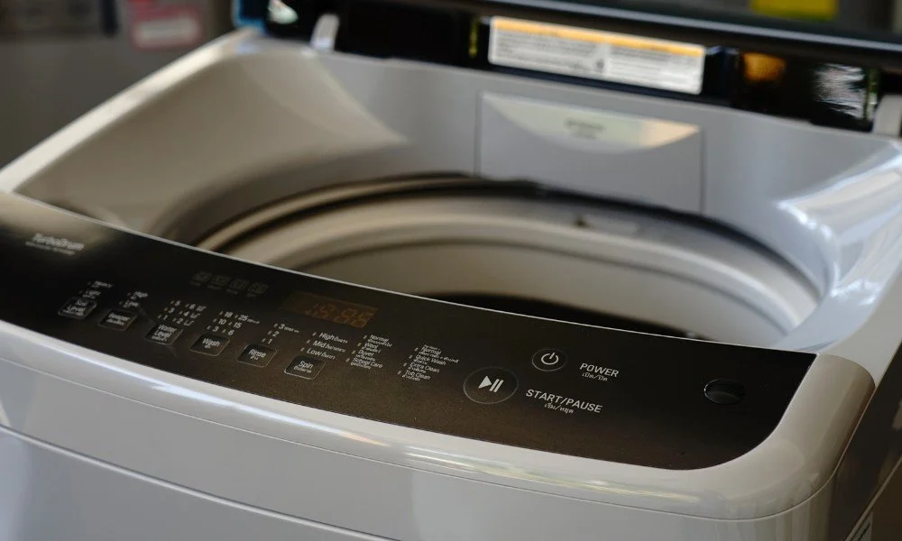Top view of a white, modern washing machine with digital controls and a partially open lid.