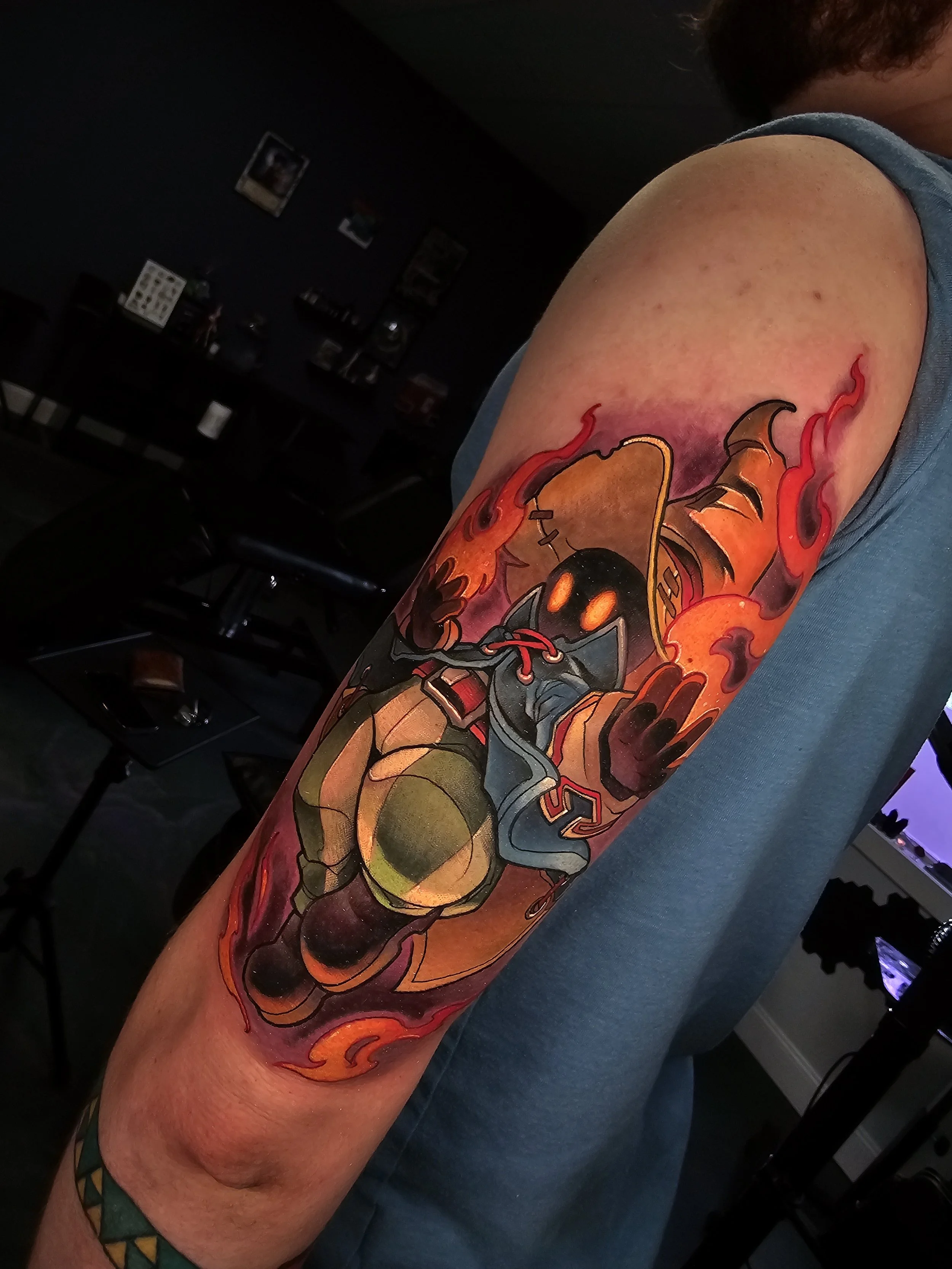 Colorful tattoo of a bomb wearing a hoodie, with flames around it, on a person's upper arm.