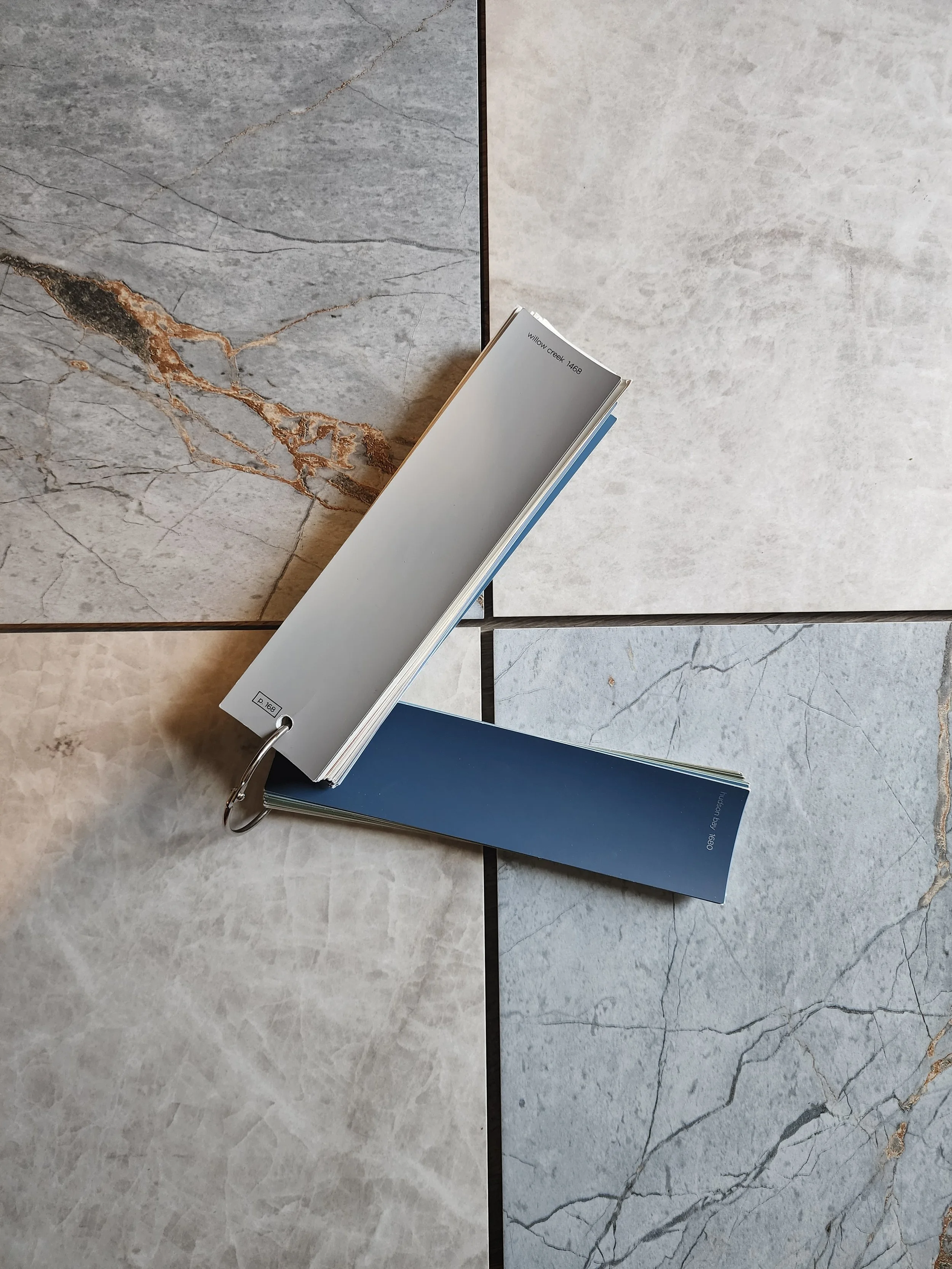 Cabinet finish sample fan deck resting on marble-look floor tile