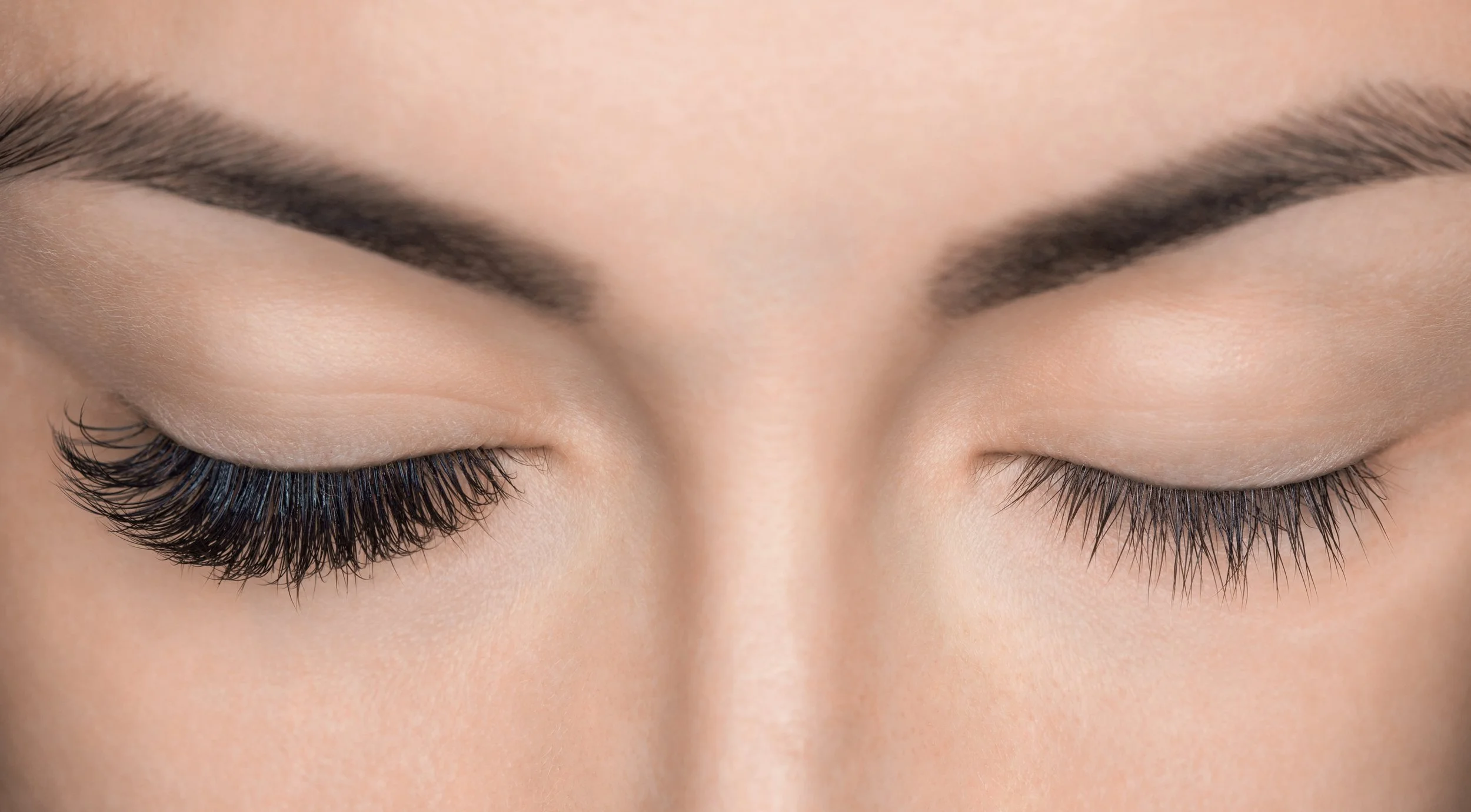 Close-up of a woman's closed eyes showing a dramatic difference between eyes, with eyelash extensions on the left eye and a natural lash lift on the right. Image used to promote eyelash extensions and lash lifts at Flirt Custom Lash Studio Toronto.