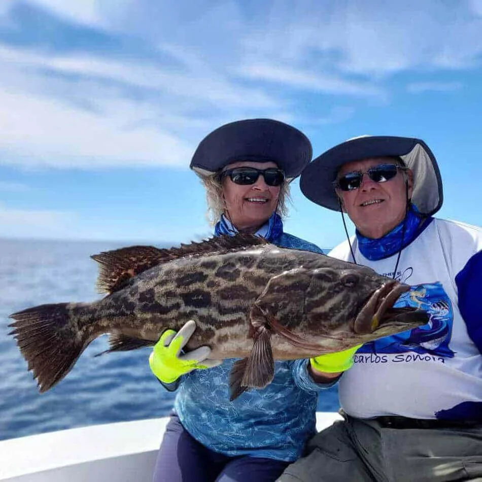 Two guests holding a large grouper aboard Fish Tale 2 private fishing charter in Guanacaste Costa Rica