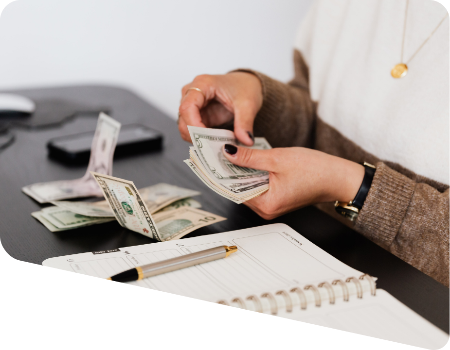 Woman's hands counting money and notebook with pen