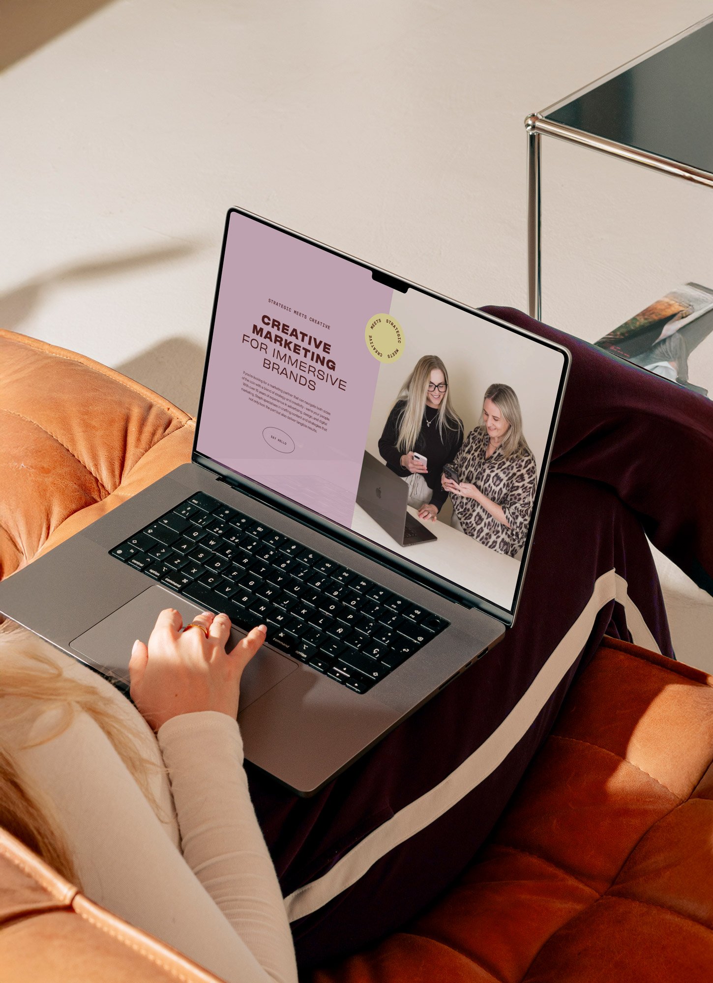 Woman sitting on coach looking at a marketing agency website featuring a brand by Foster Creative.