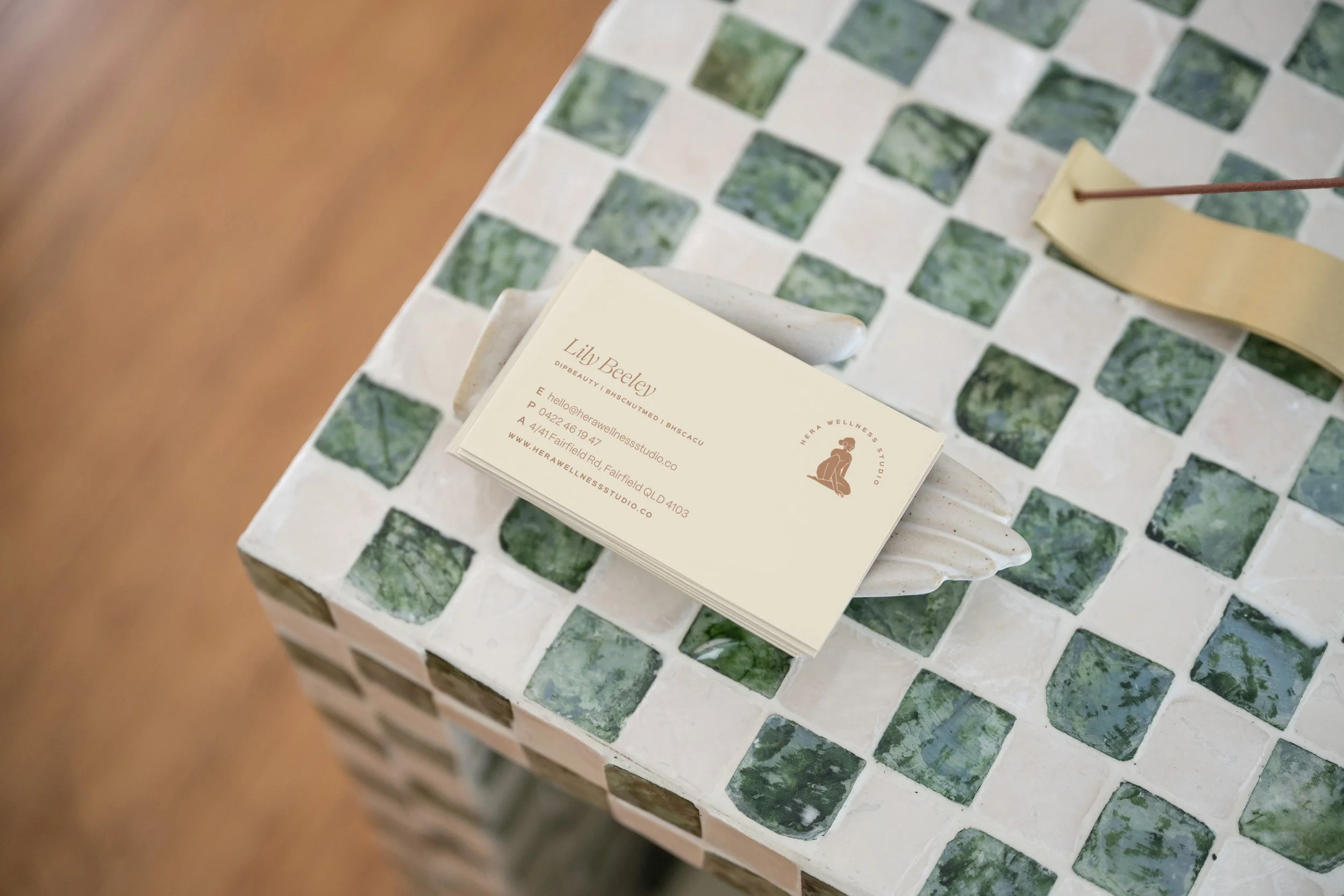 A beauty business business card design placed on a surface with green and white tiled pattern.