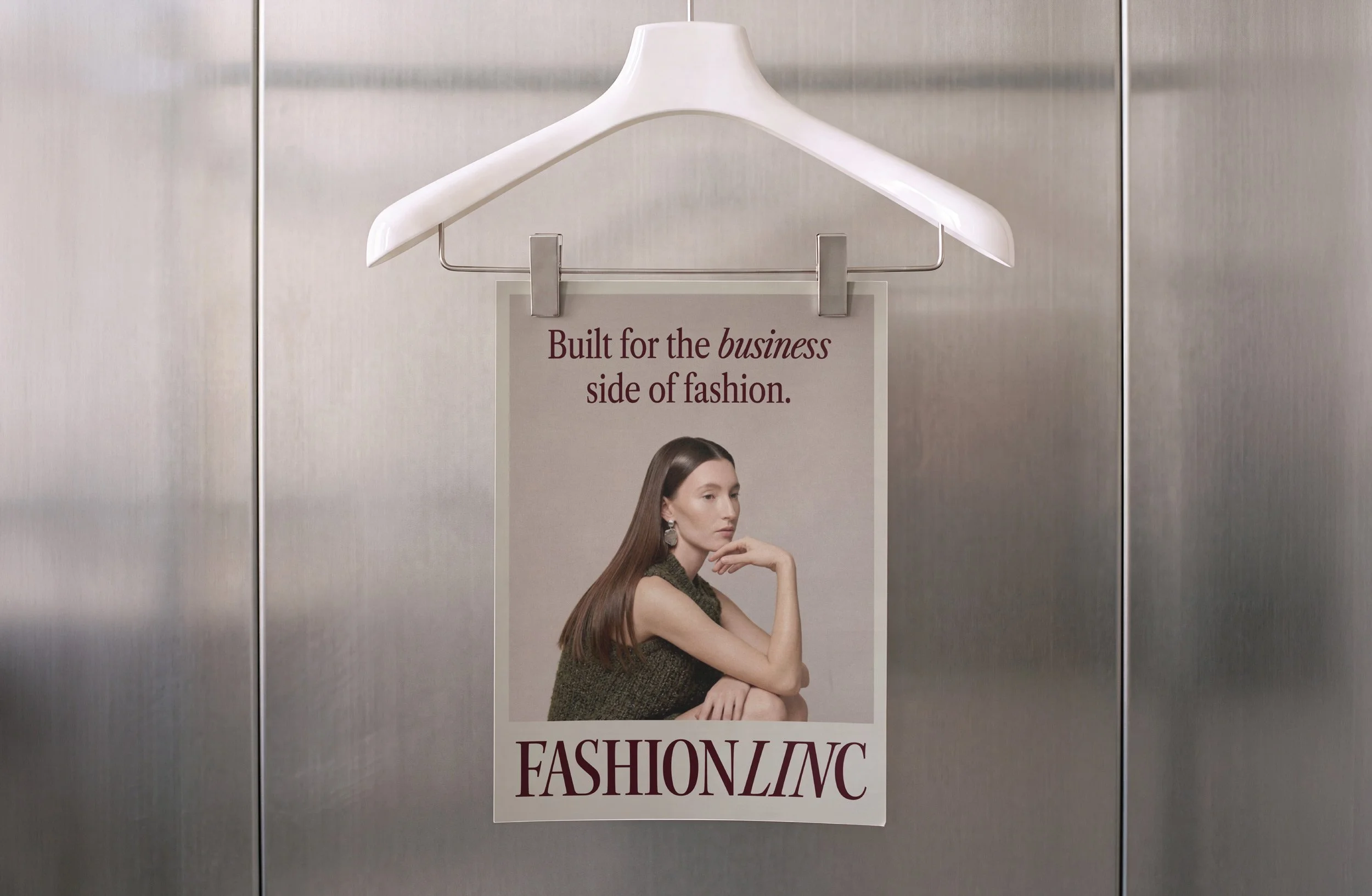 Fashion brand campaign poster hanging on a white hanger in a showroom.