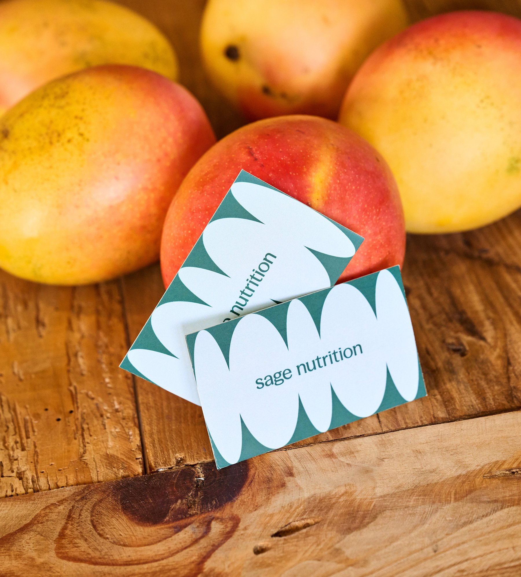 Business cards reading Sage Nutrition leaning against mangos.