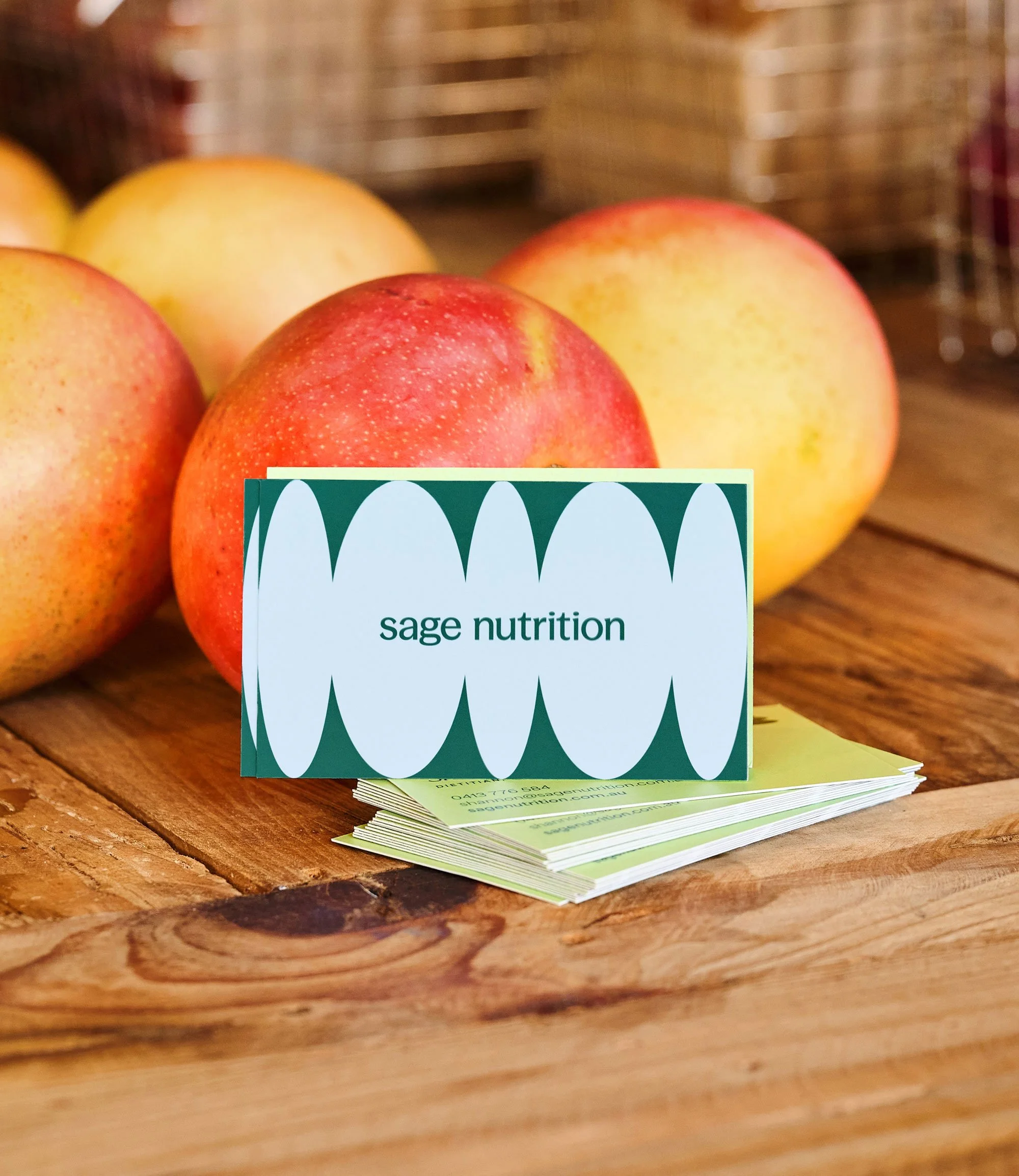 Photo of business cards for a nutritionist sitting on a wooden table with mangoes.
