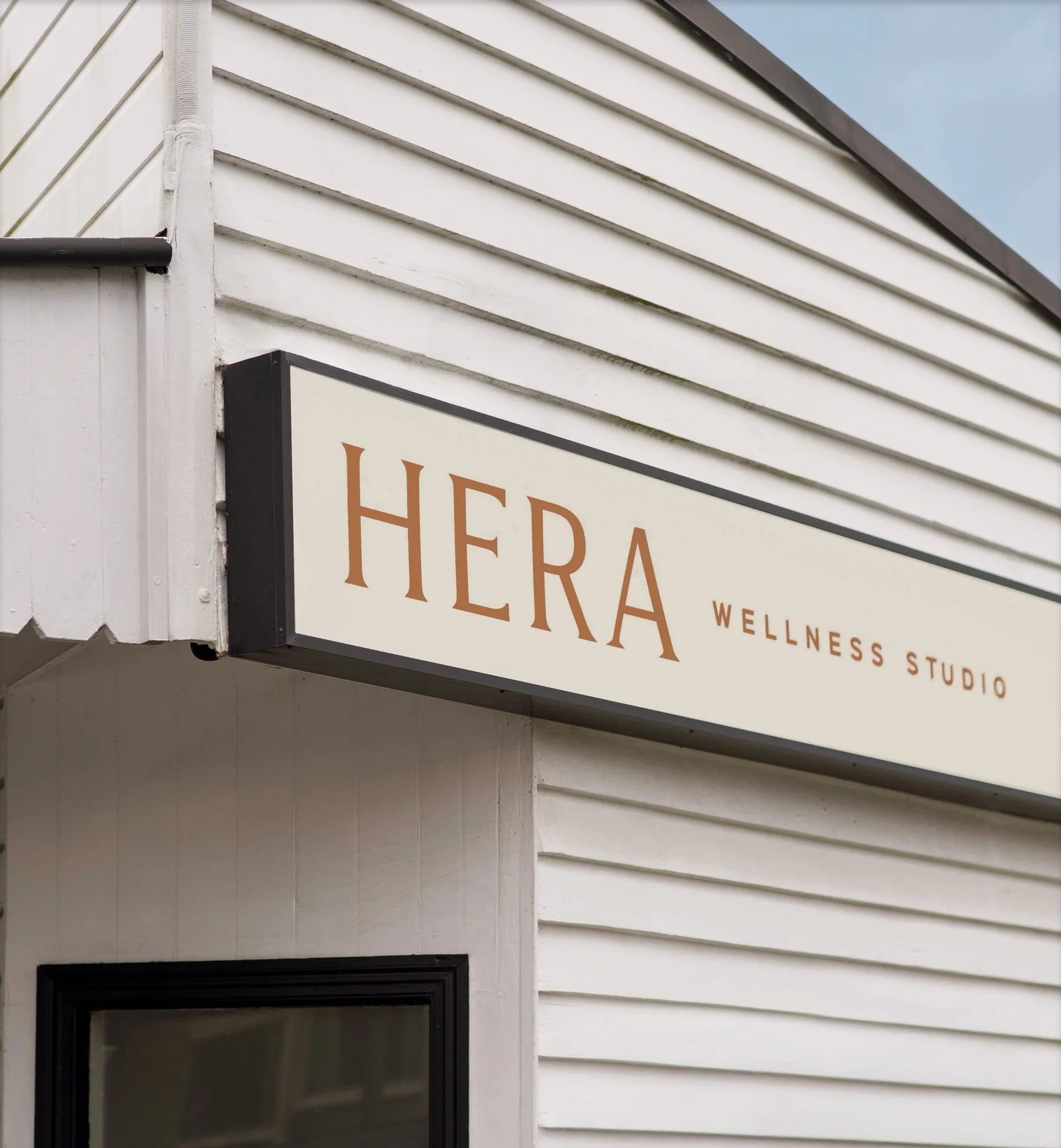 Close-up of a building corner with signage reading 'HERA WELLNESS STUDIO' using branding by Foster Creative.