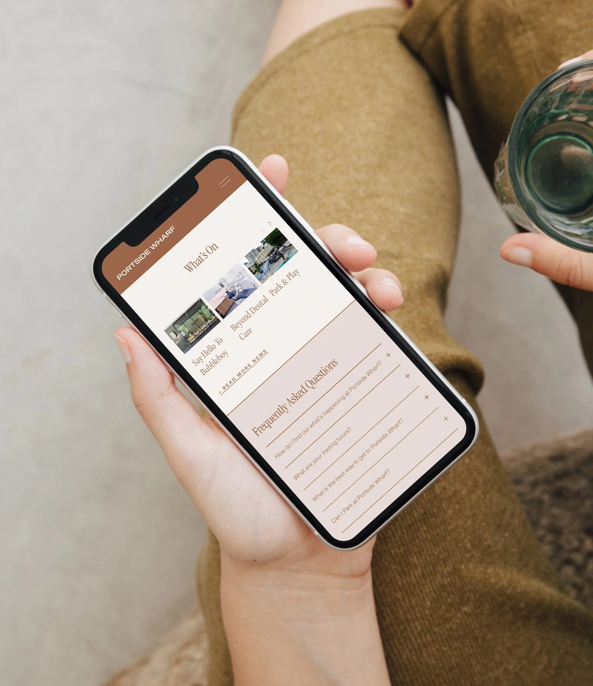 Woman's hand holding mobile with a mockup of the Portside Wharf website.
