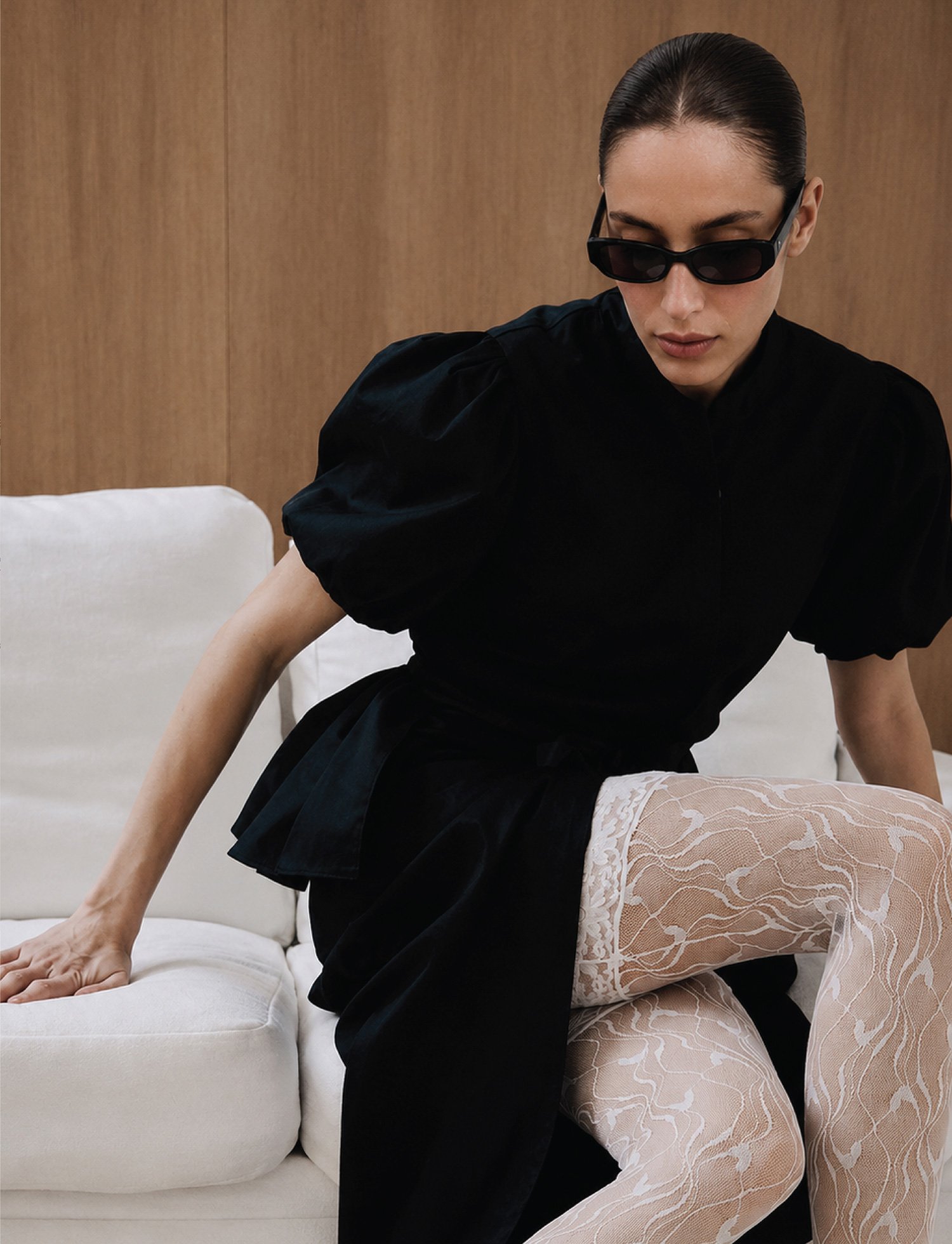 A fashion model in black clothing and sunglasses as part of a fashion brand campaign imagery.