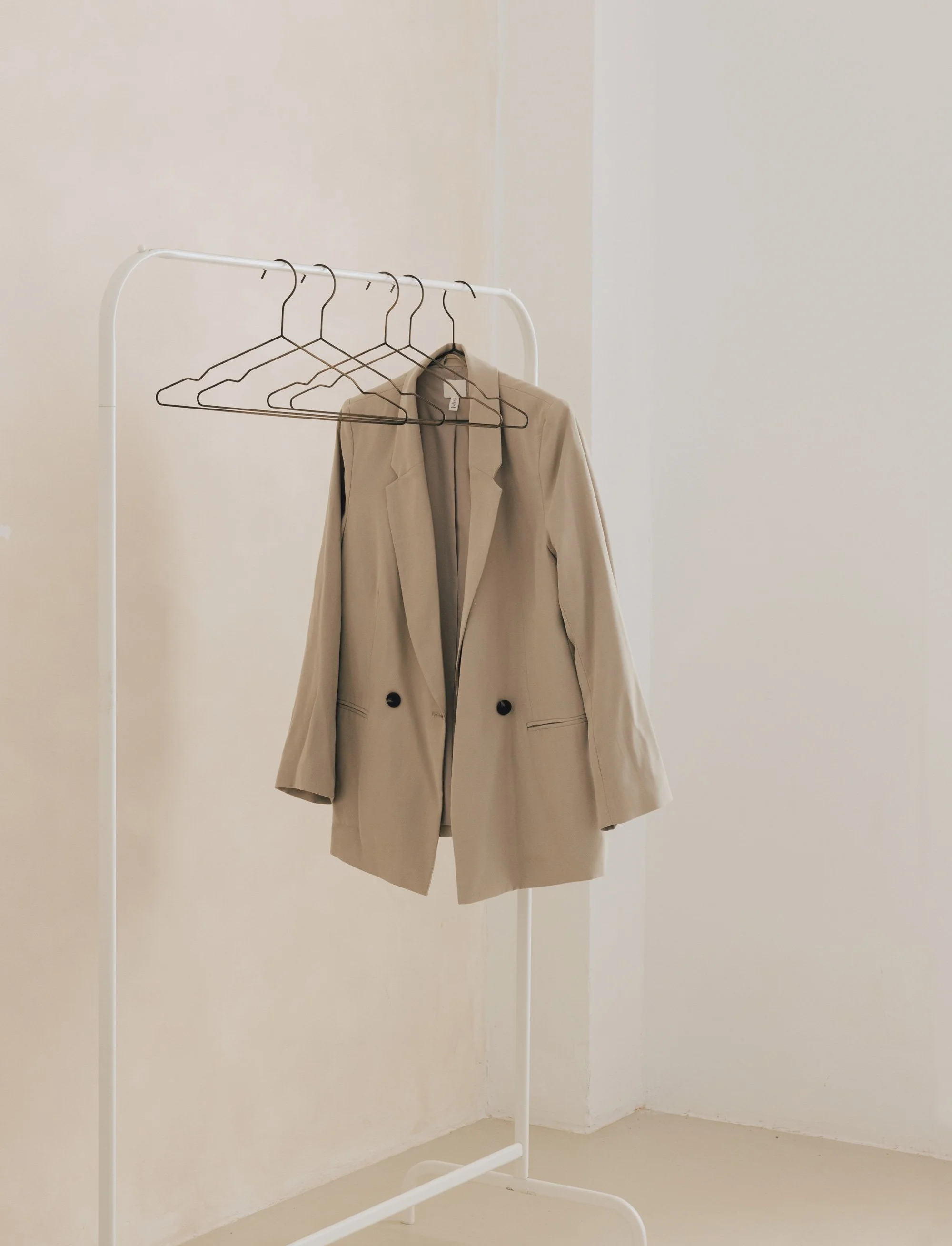 A beige blazer hanging on a clothing rack in a fashion showroom.