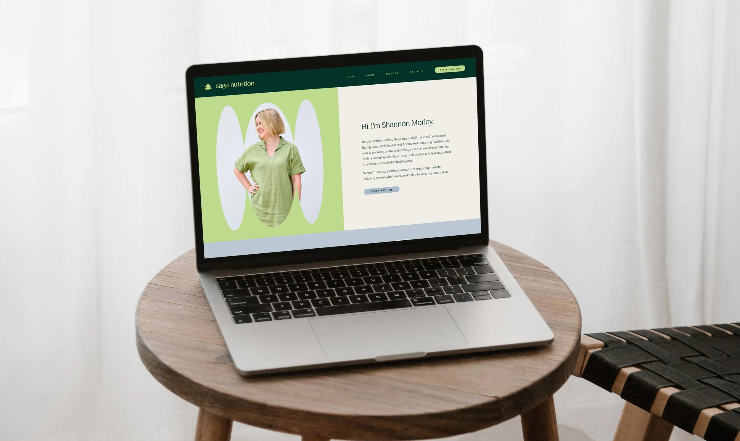 Laptop on a wooden table displaying a webpage about Sage Nutrition, featuring a woman in a green shirt and text introducing Shannon Morley, a dietitian.