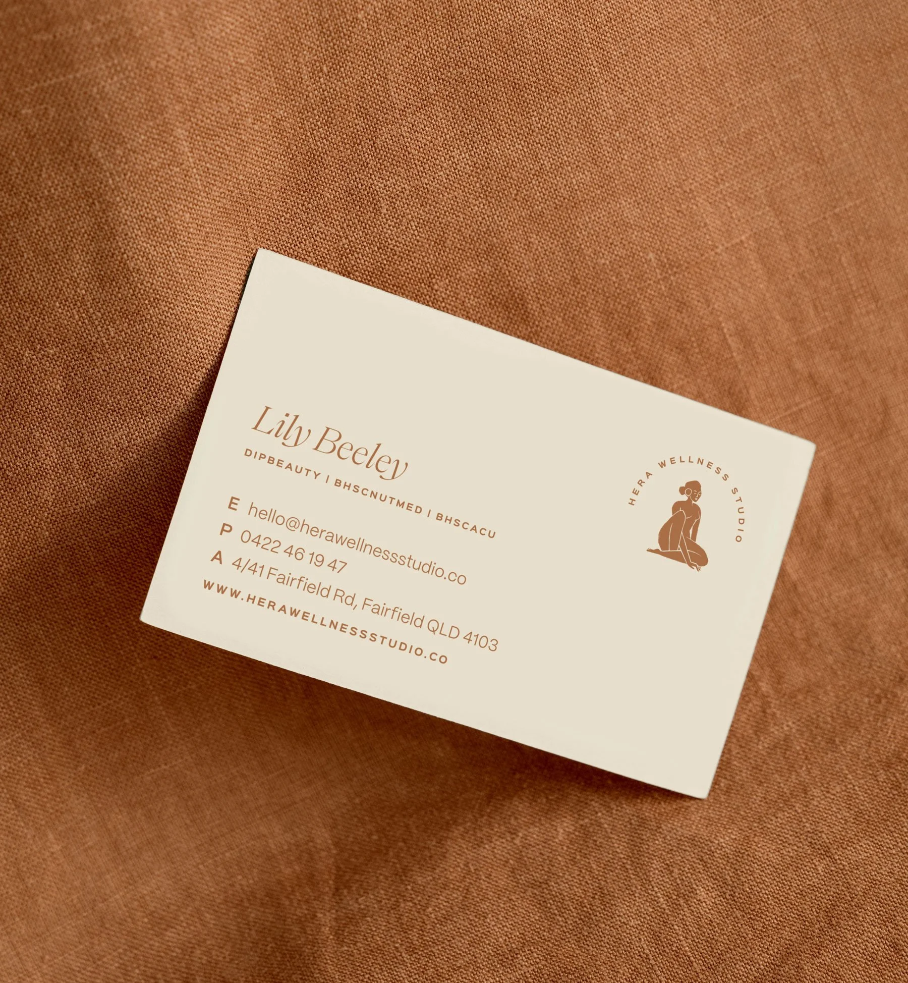Business card for a health and wellness studio, designed by Foster Creative, on a brown textured fabric surface.