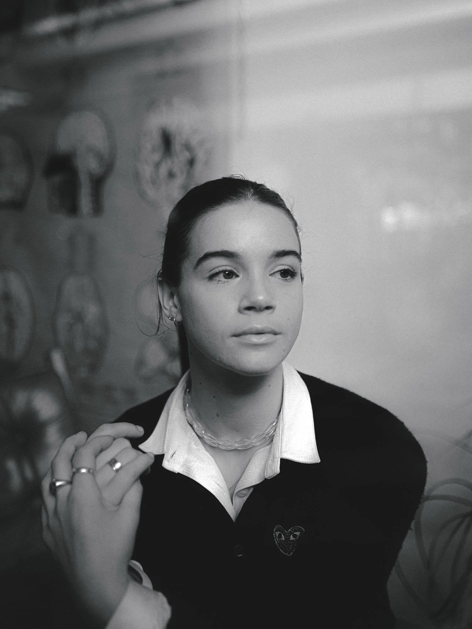 A woman with dark hair sitting by a window, staring into the distance