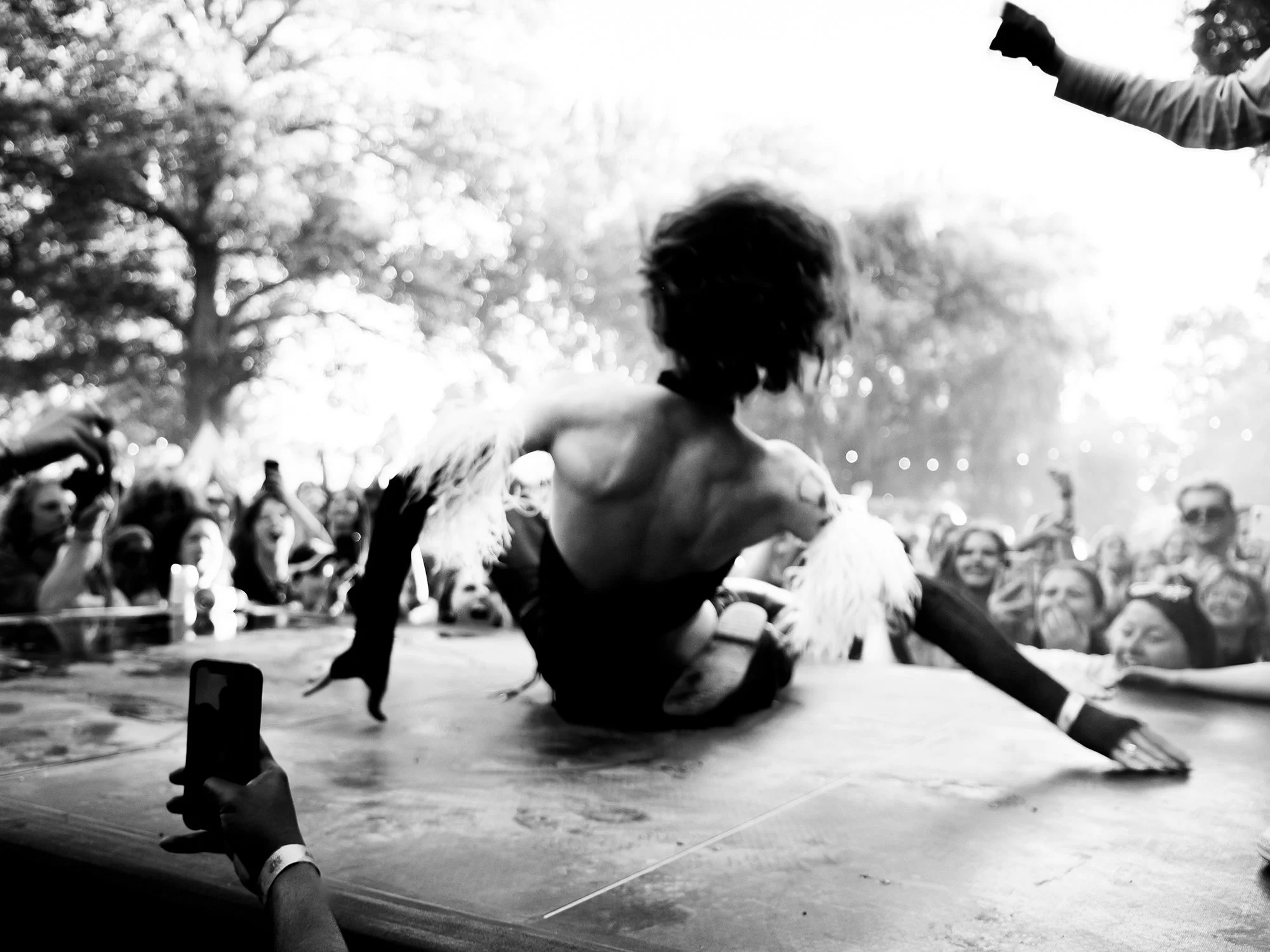 A dancer on an outdoor stage is watched by a crowd