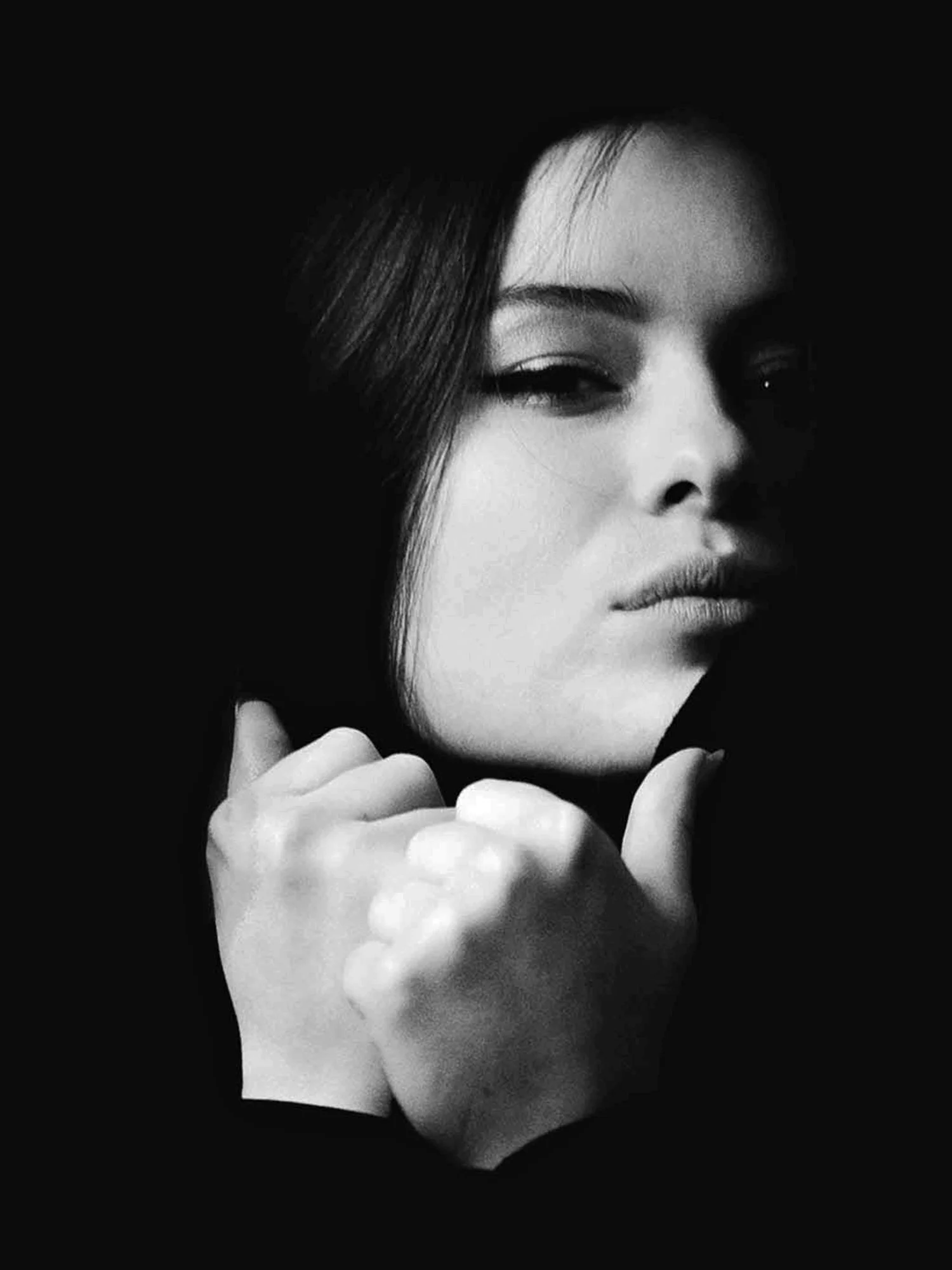 A close up portrait of a young woman holding her jacket collar