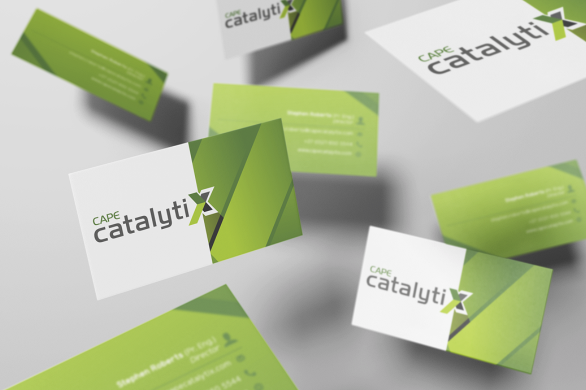 Business cards and flyers with a green and white design and the logo 'Cape CatalytiX' on a flat surface.