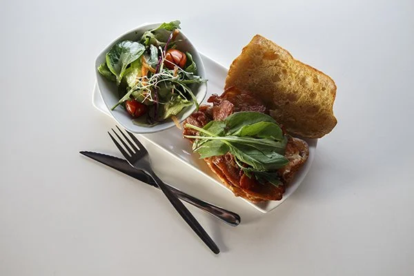 A plate with a small side salad, a meatball sub sandwich, and a large piece of garlic bread.
