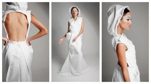 Fashion photoshoot featuring three models in white outfits. The first model shows her back, revealing an open-back dress. The second model stands confidently in a fitted, elegant white gown. The third model is in profile, wearing a hooded white outfi