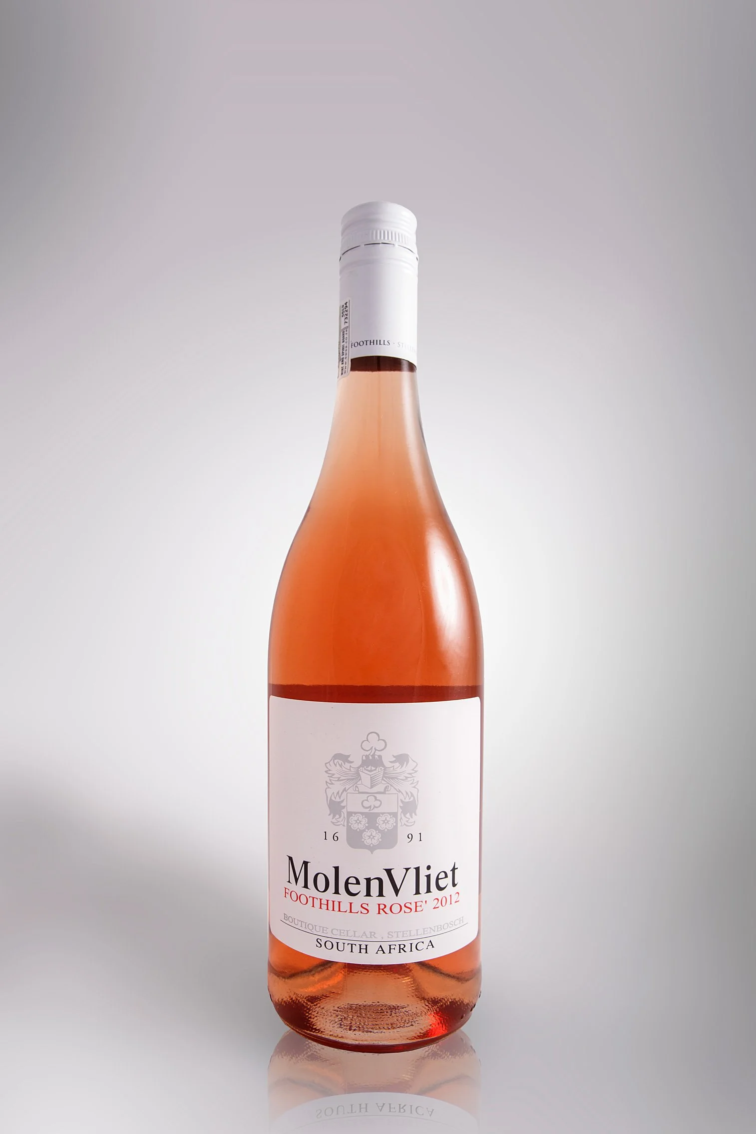 A bottle of MolenVliet Foothills Rose 2012 wine from South Africa, with a white label and a white cap, standing on a reflective surface.
