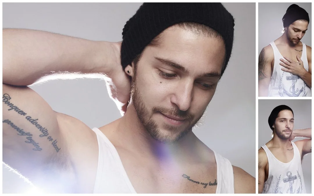 A collage of three images of a man with dark hair, tattoos, and a beard. In the main image, he is wearing a black beanie and a white tank top, with one hand behind his head, looking down. In the top right, he is in the same outfit, holding his chest 