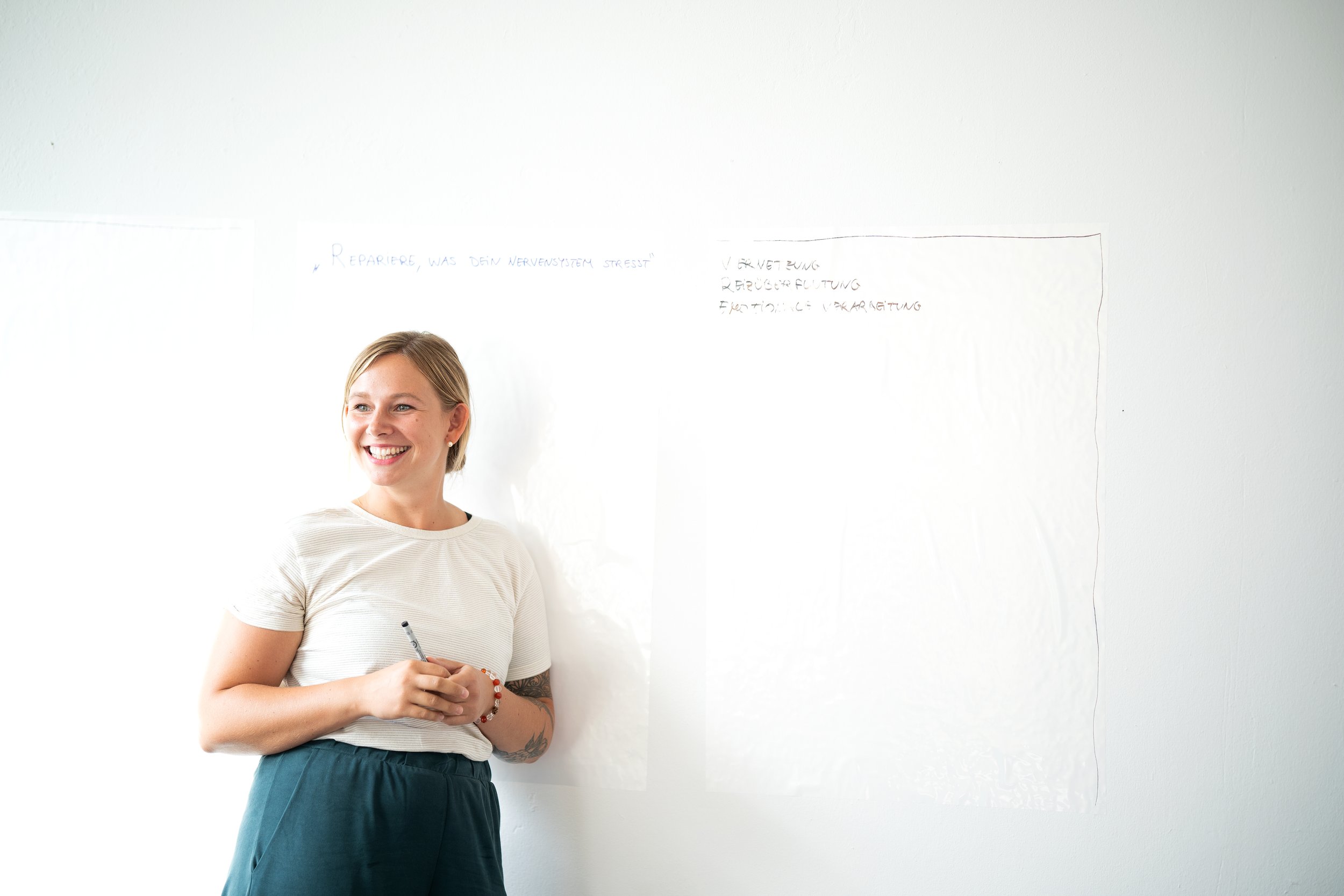 Lächelnde Frau vor einem Whiteboard mit einem Stift in der Hand.
