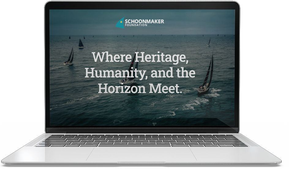 Laptop displaying a website with sailboats on the ocean and the text "Where Heritage, Humanity, and the Horizon Meet."