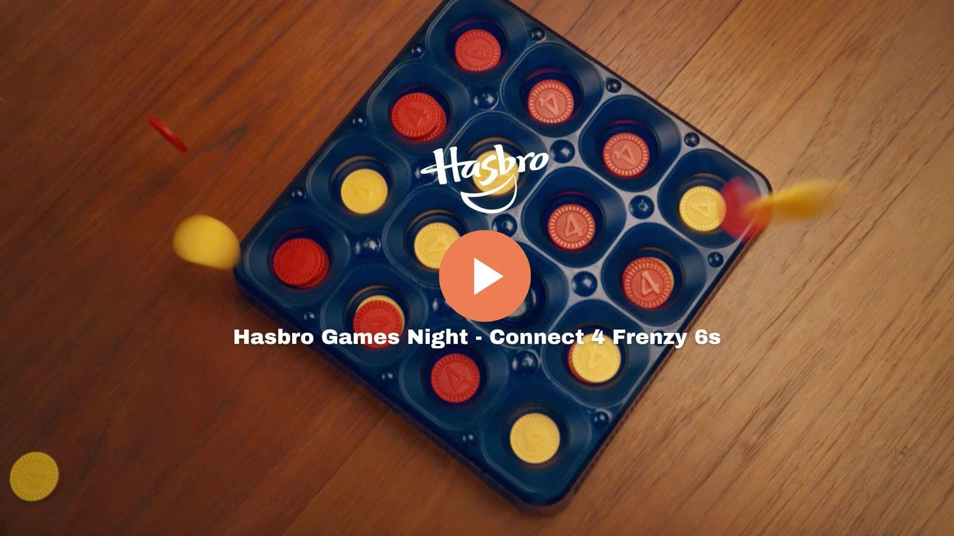 A colorful Connect 4 game on a wooden surface with yellow and red game pieces in motion, some on the game grid and others falling into the slots.