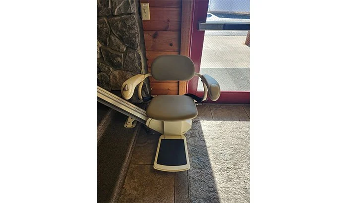 A stair lift featuring a comfortable seat and footrest, branded with the Salt Lake Stairlifts logo.