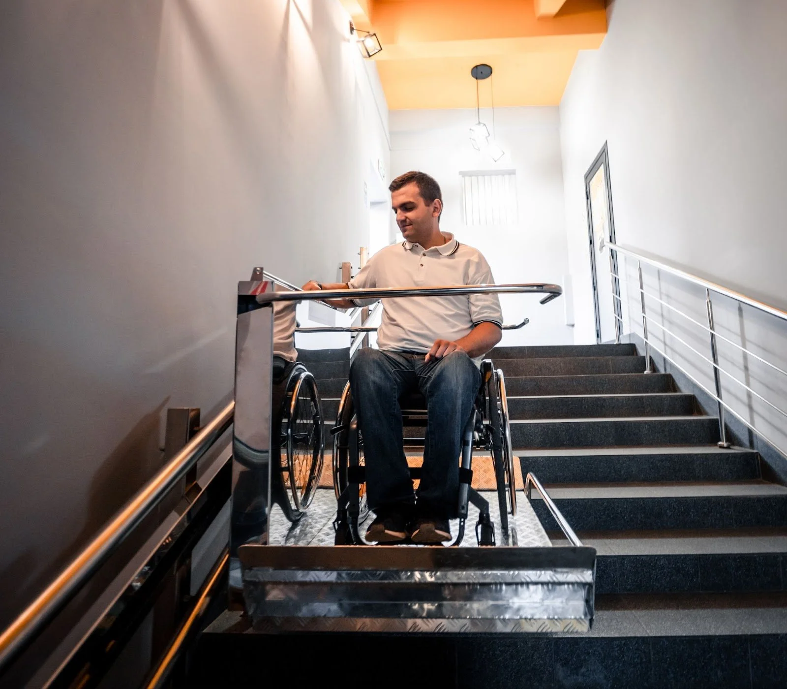 A man in a wheelchair safely navigating stairs of a building, showcasing the safety benefits of accessibility