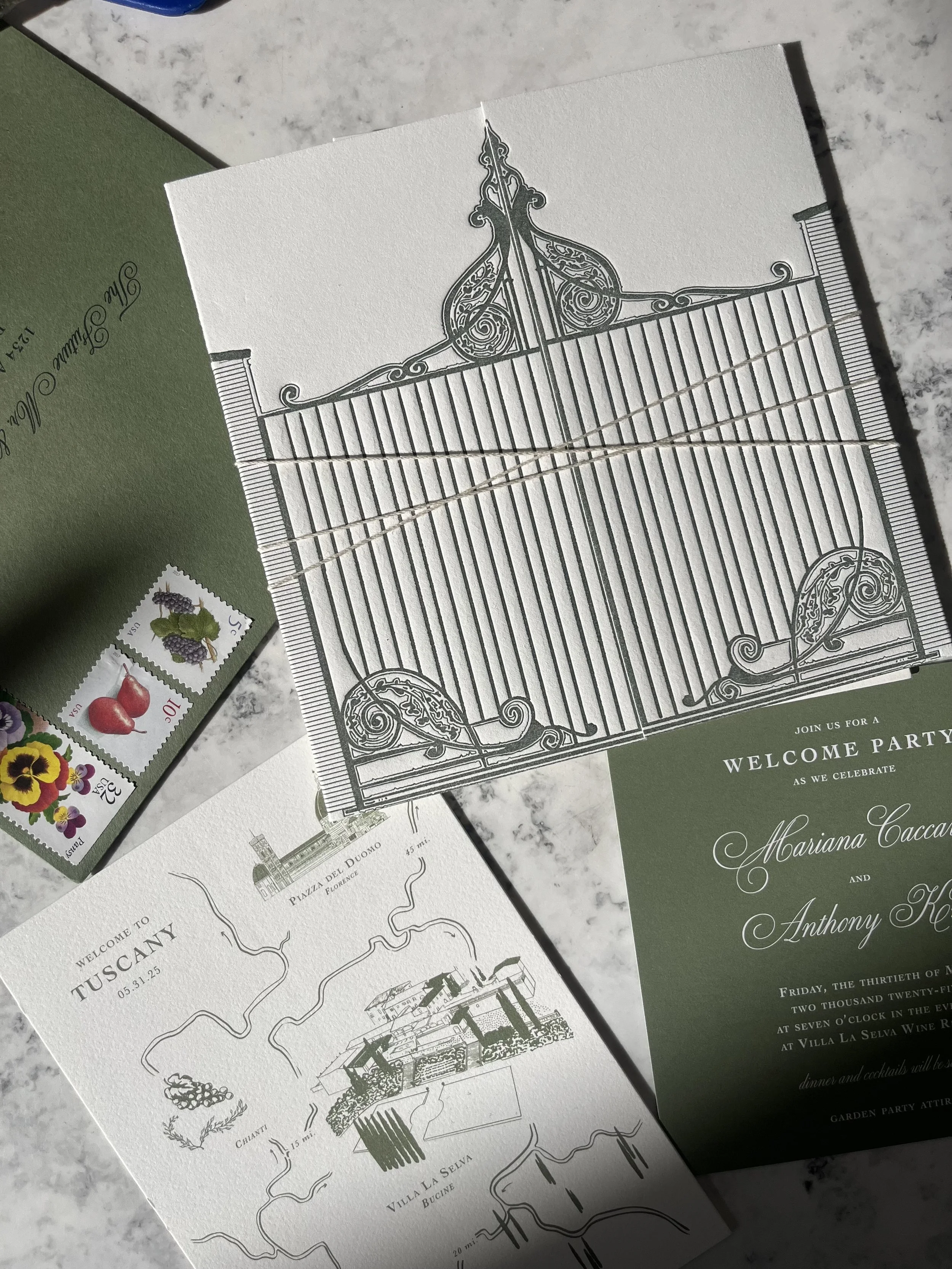 Wedding invitation suite with green and white color scheme, featuring a detailed tavern gate illustration, a map of Tuscany, Italy, with landmarks and vineyard, and floral stamps.