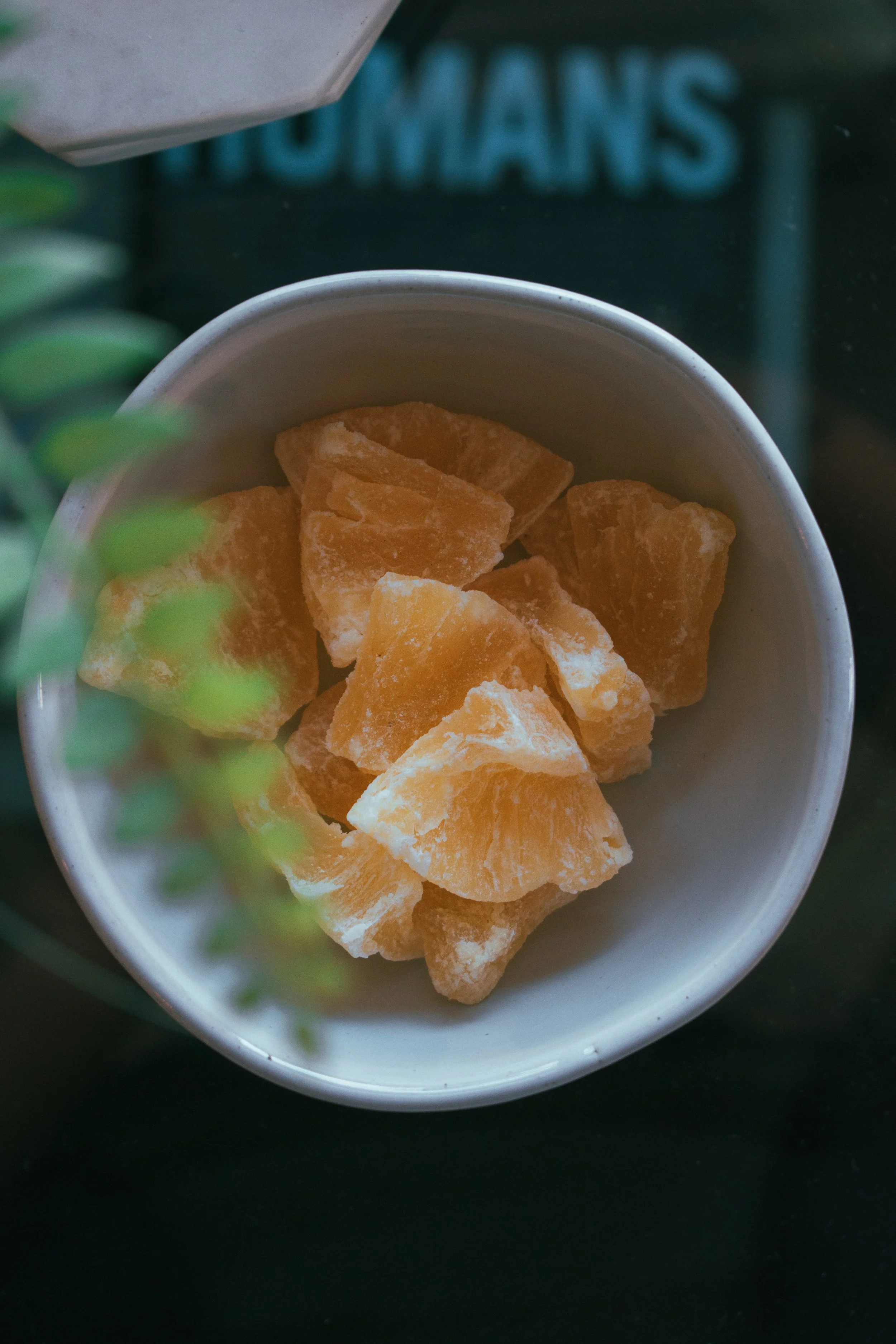 A white bowl filled with dried orange fruit pieces in front of a dark background.