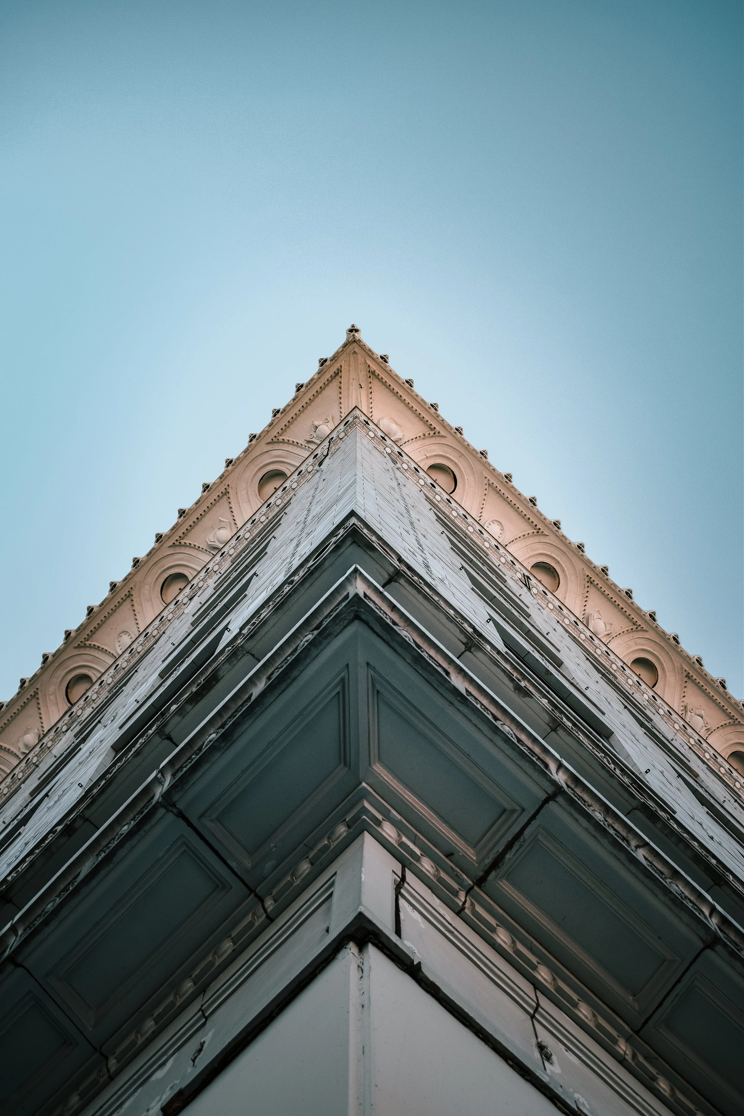 Low-angle view of a corner of a historic building with detailed decorative architecture against a clear sky.