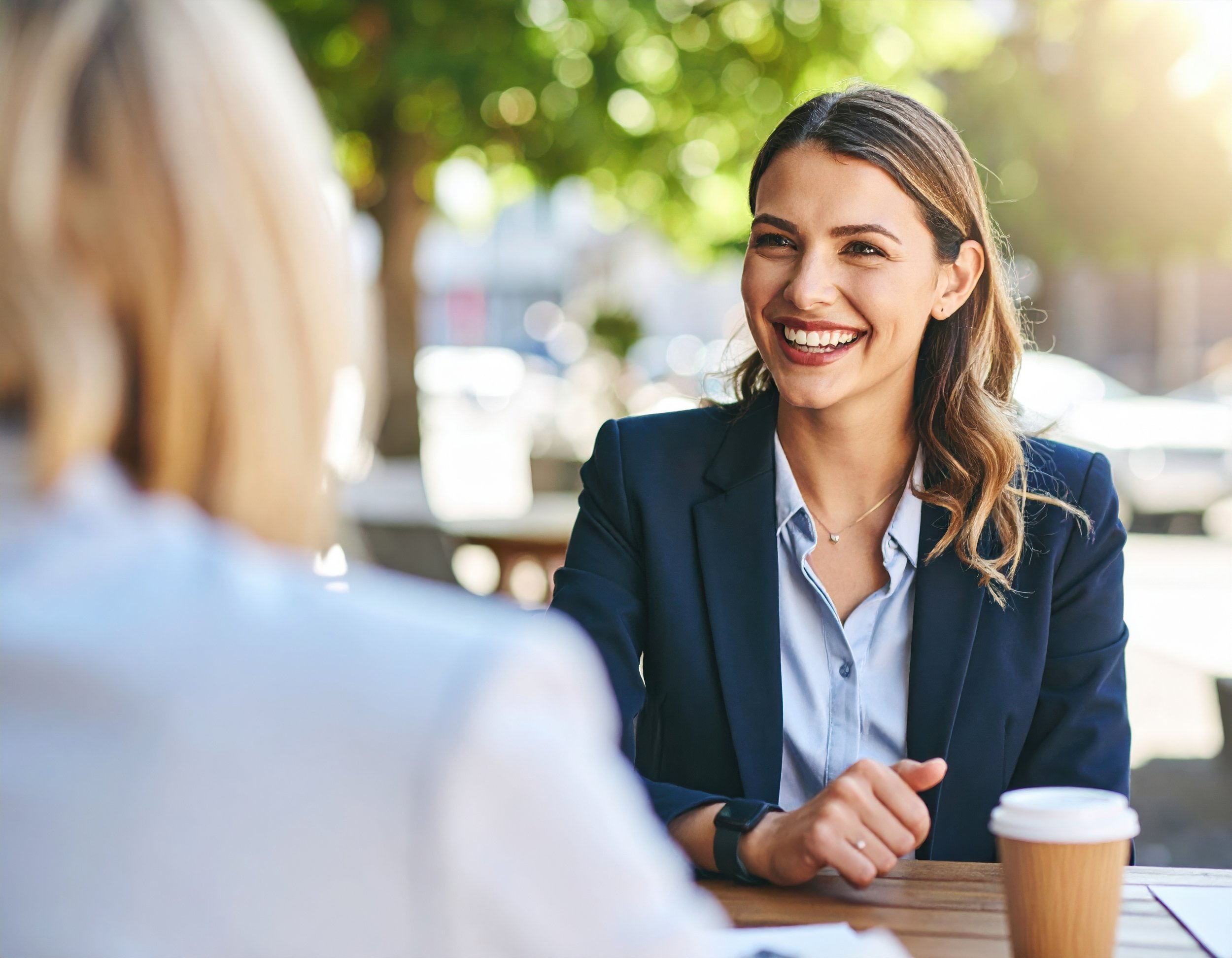 two women sitting outside, having a coffee meeting