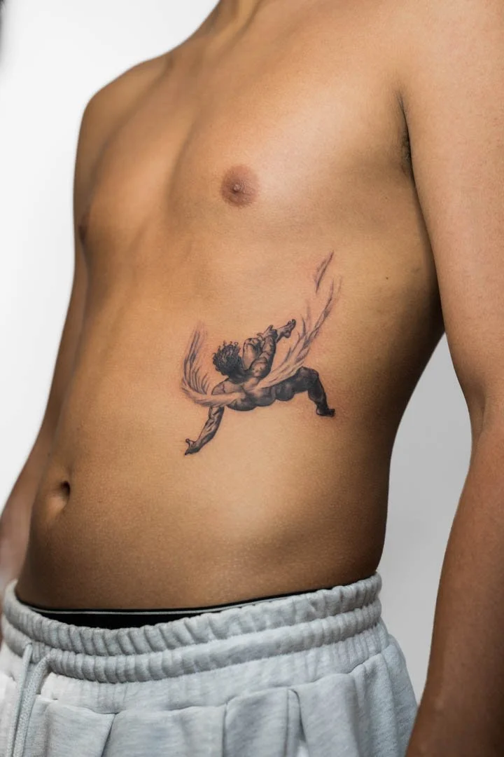 Tattoo of the Greek mythological character Icarus falling from the sky. The placement is on the side of the rids. The tattoo is in the black and grey realism style.