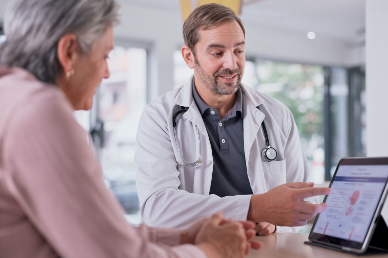 Dr. med. Christian Hirschner erklärt einer Patientin die Ursachen schmerzender Krampfadern anhand einer digitalen Befunddarstellung im MVZ Chirurgie Kiel.