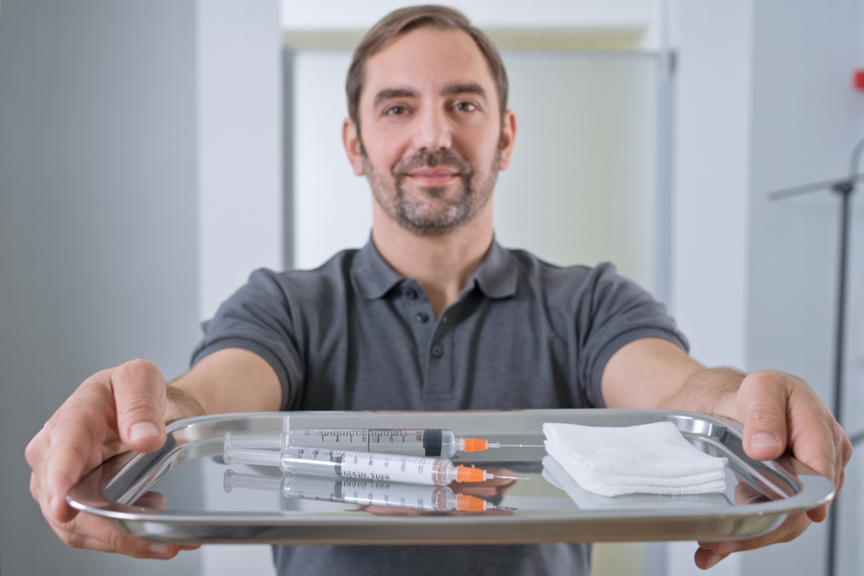 Flüssigverödung und Schaumverödung bei Krampfadern im direkten Vergleich. Dr. Hirschner hält ein Tablett mit zwei Spritzen.