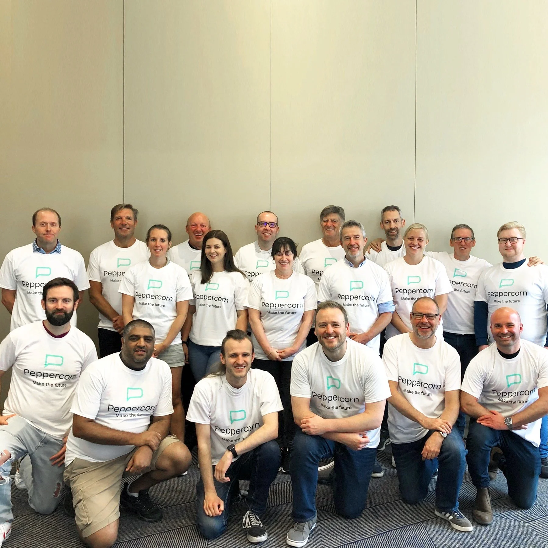 A photo of the Peppercorn team. Photo shows team members in white t-shirts smiling at the camera.