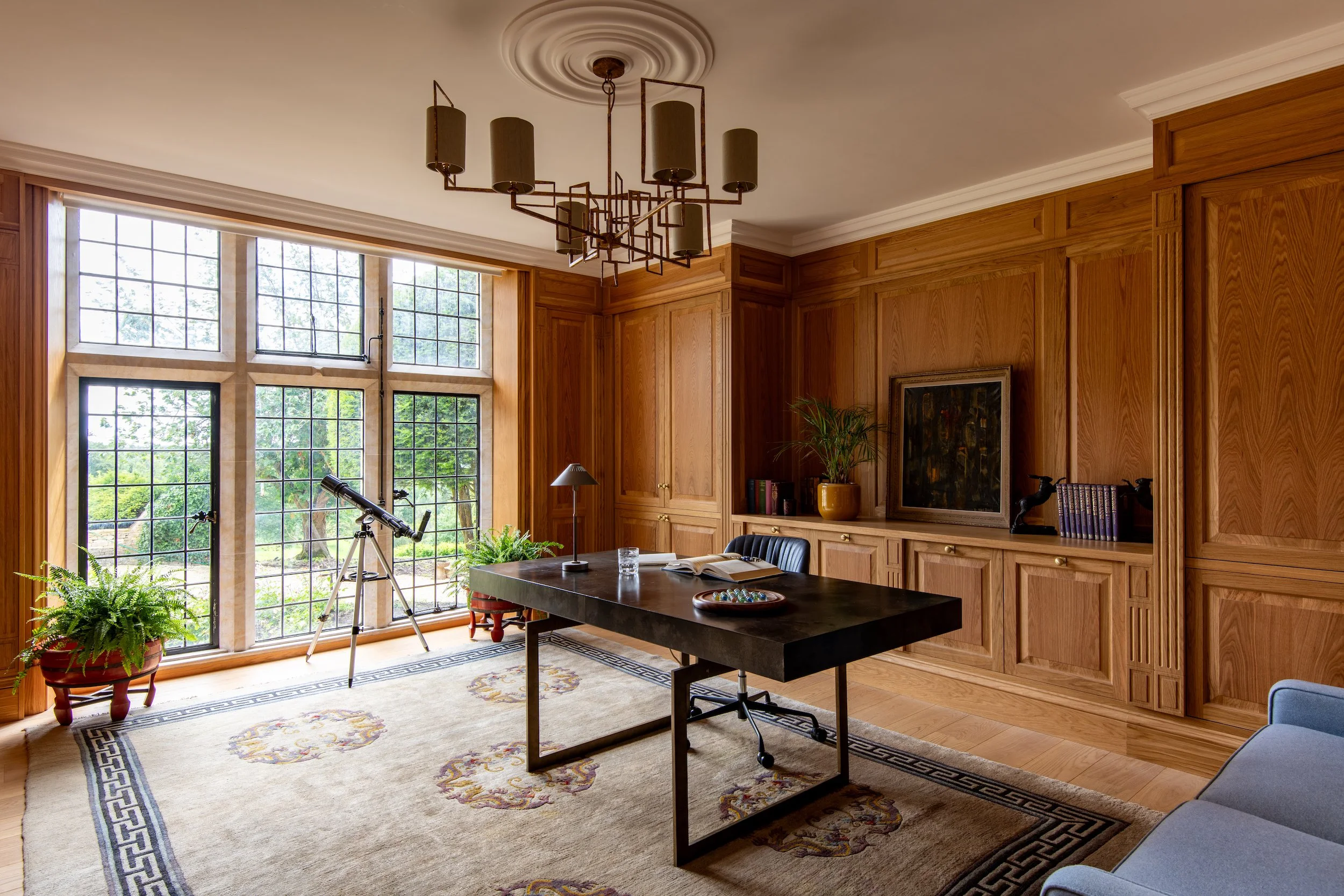 Study designed by MIDA Interiors for a large Cotswolds country estate, featuring bespoke oak panelling, tailored storage, integrated lighting, motorised blinds, timber flooring with underfloor heating and an antique rug for acoustic softness.