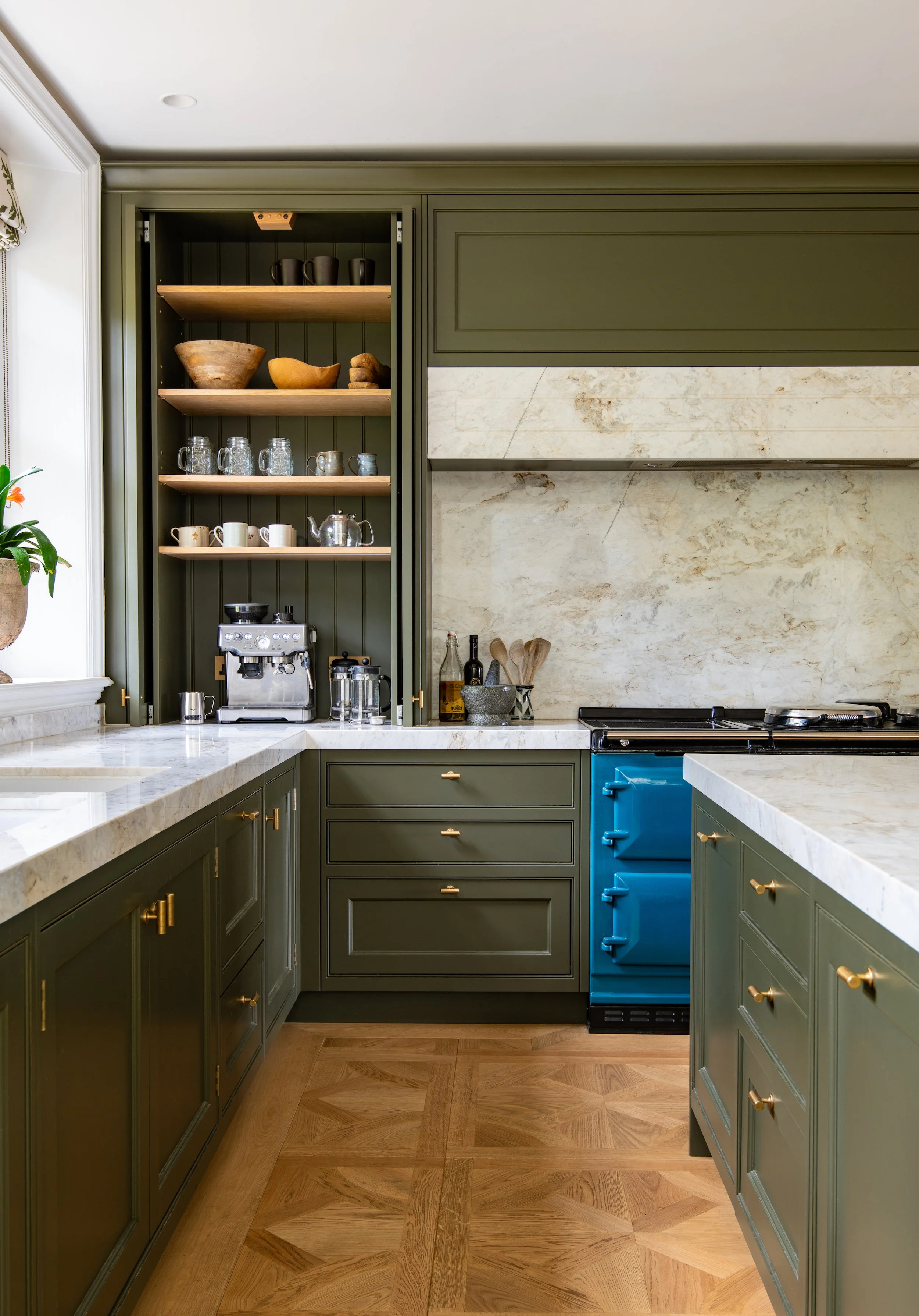 Bespoke kitchen reconfigured and designed by MIDA Interiors for a large Cotswolds country estate, featuring handcrafted cabinetry, a generous island planned around the client’s cooking style, a teal electric Aga and Calacatta Firenze stone sourced fr