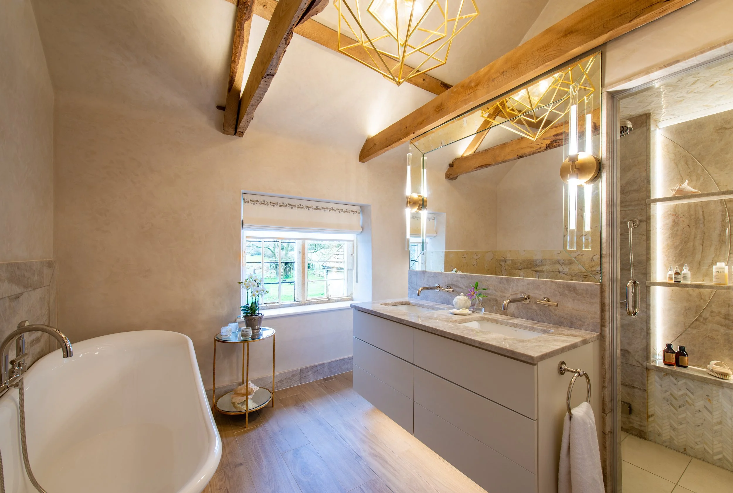 The principal bathroom combines the character of the farmhouse with the comfort of a contemporary private spa. Original exposed timbers sit above a deep freestanding soaking bath, wall-hung double vanity and generous steam shower. Veined stone, softl
