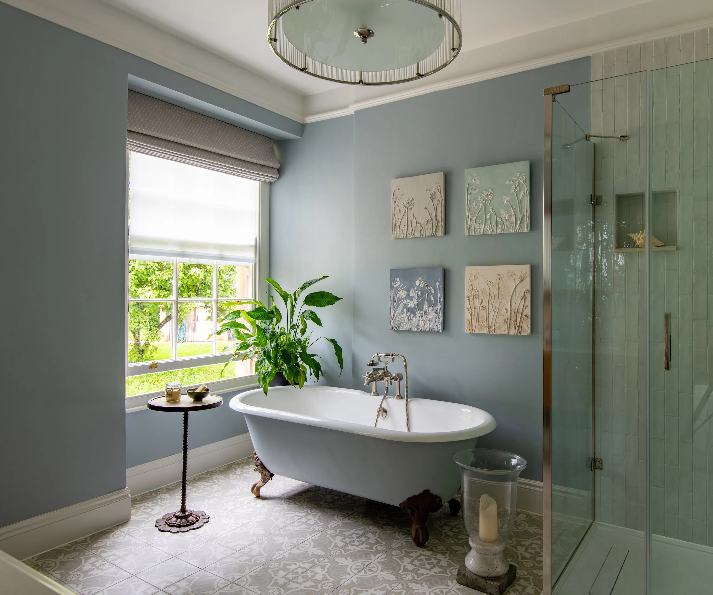 Principal guest en-suite bathroom designed by MIDA Interiors for a large Cotswolds country estate, created by opening into an adjoining bedroom and featuring a freestanding reclaimed roll-top bath, generous walk-in shower, decorative floor tiles.