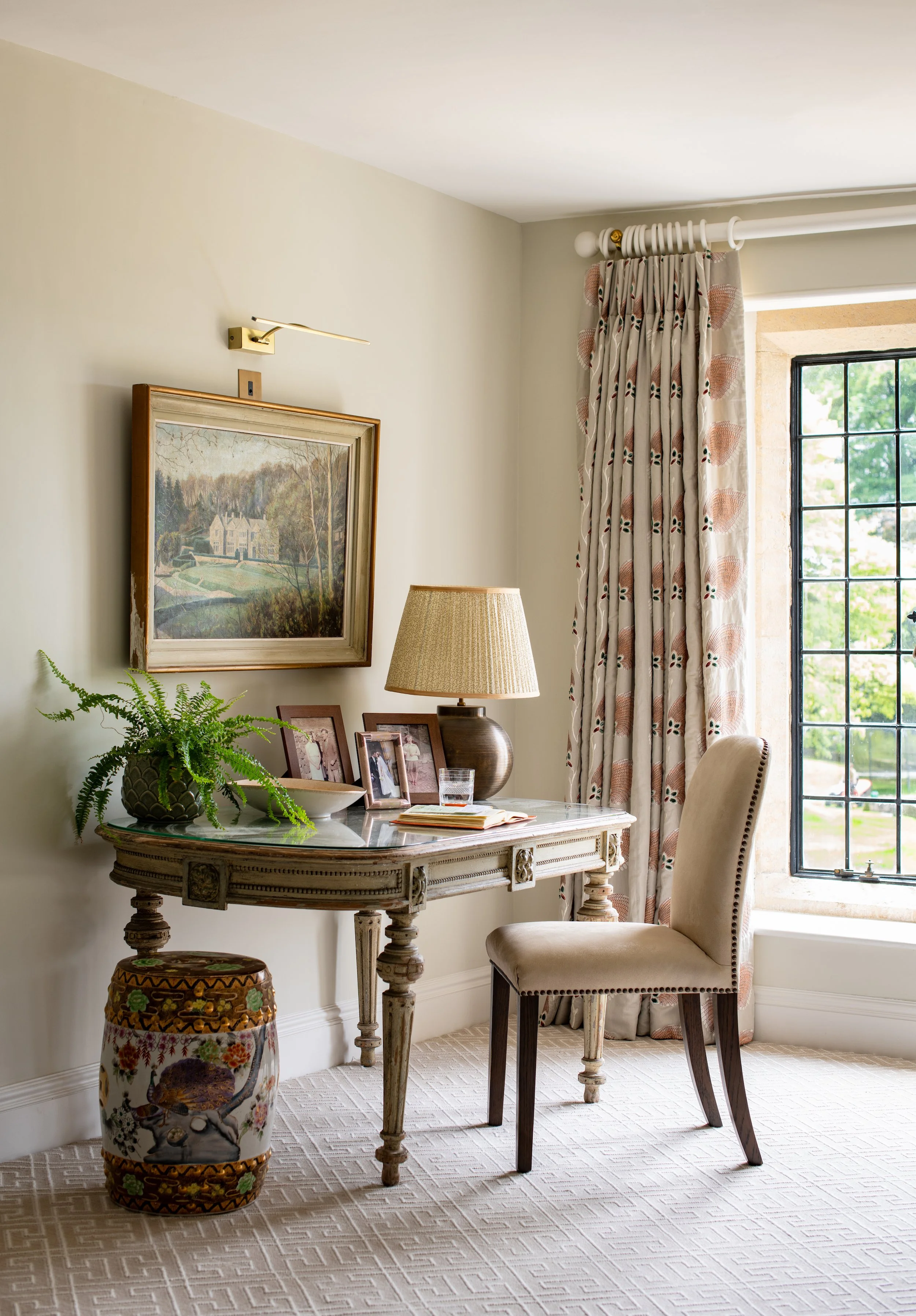 Upper landing home office designed by MIDA Interiors as a quiet secondary workspace, featuring an antique writing desk, tailored curtains and views across the Cotswolds estate.