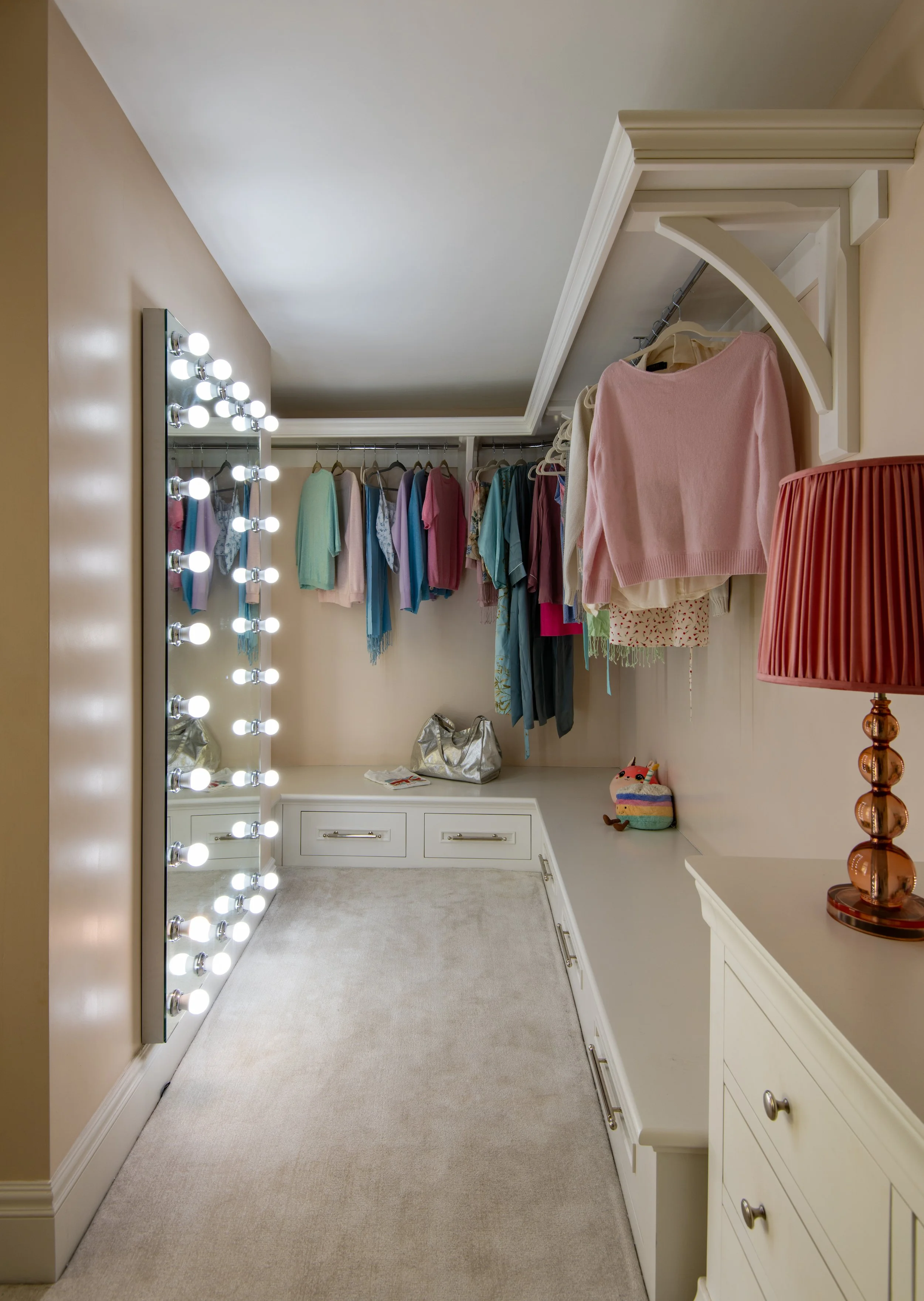 Children’s dressing room designed by MIDA Interiors for a large Cotswolds country estate, featuring bespoke open storage, integrated drawers, a full-height illuminated mirror and glazed partitioning that brings natural light into the reconfigured spa