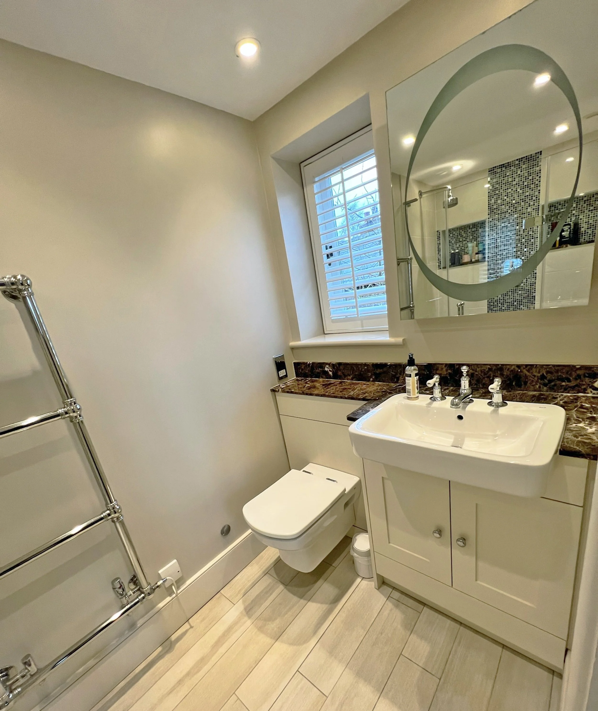 Compact principal en suite with a fitted vanity, dark stone worktop, statement mirror, traditional fittings and discreet integrated storage.