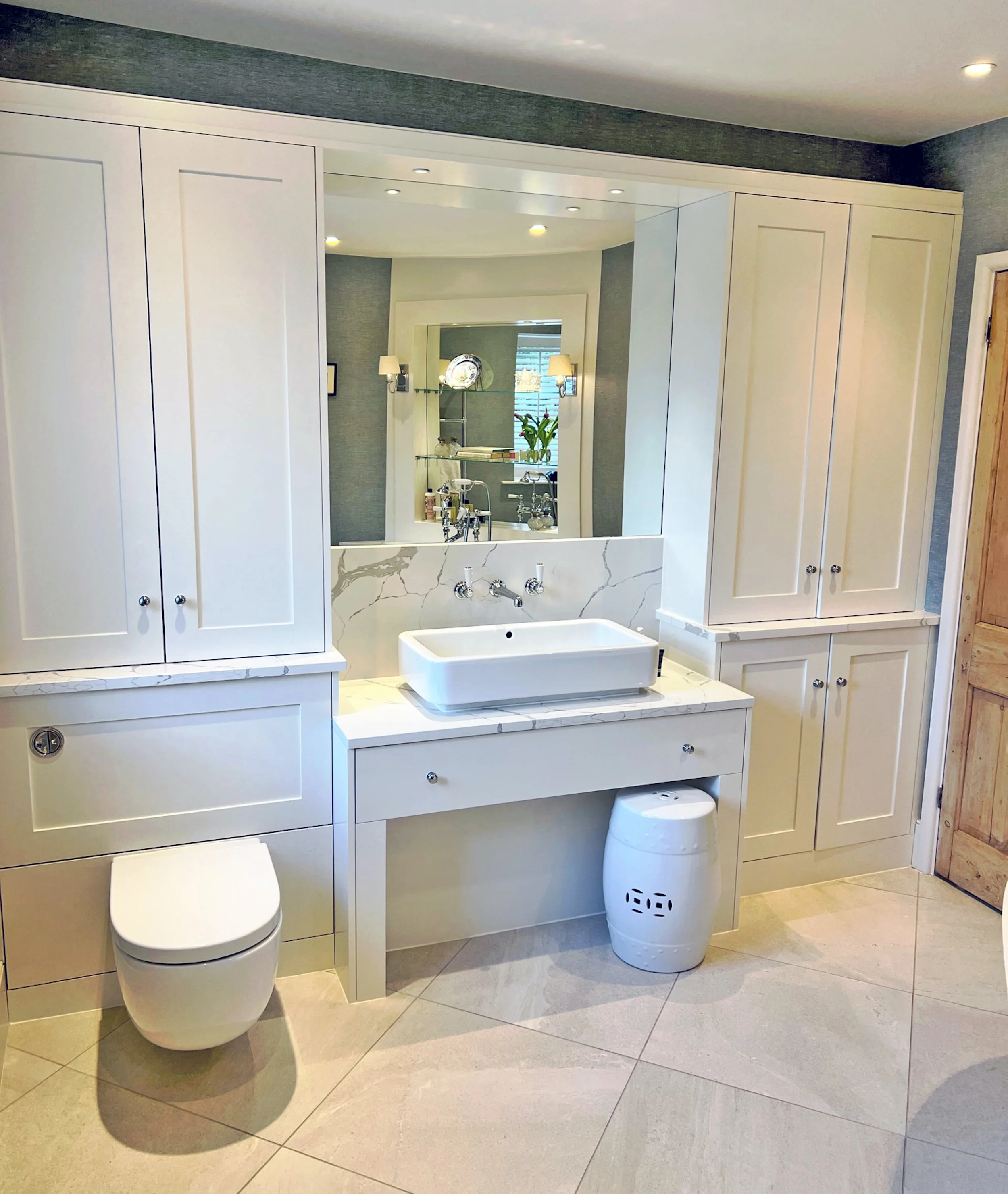 Bespoke joinery in the reconfigured Jack and Jill family bathroom, with a stone topped vanity, integrated storage and linen-look wallpaper.