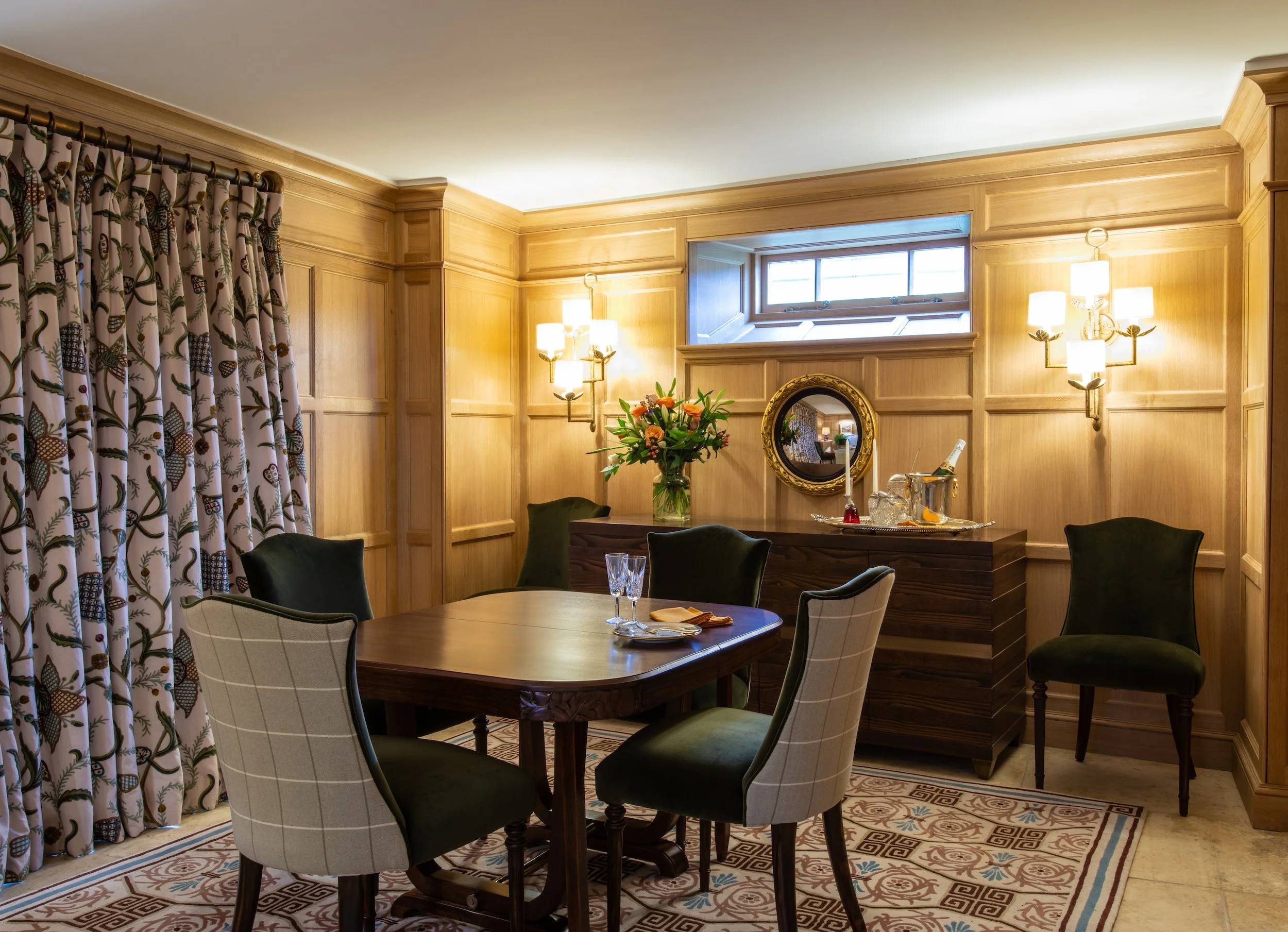 A comprehensively reconfigured dining room within a Grade II listed Cotswold farmhouse. Handcrafted oak panelling responds to the room’s unusual proportions while discreetly concealing integrated storage. Crewelwork curtains, contemporary wall lighti