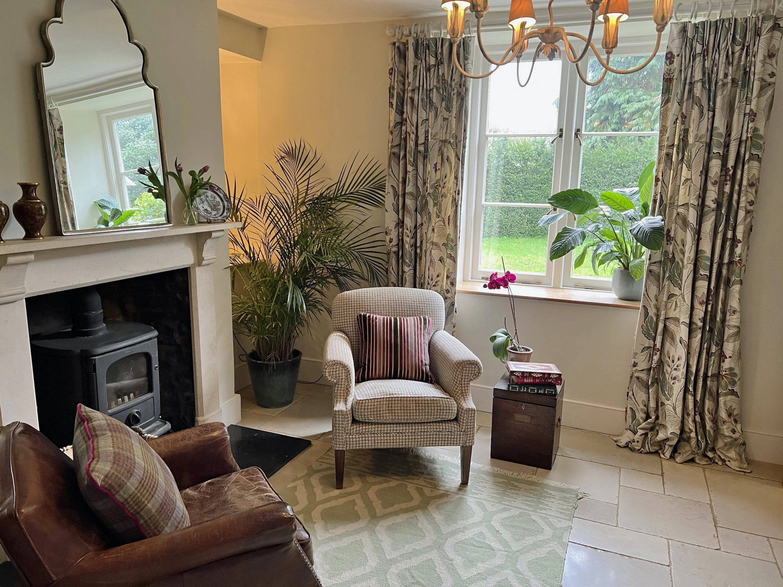 Front hall of a 19th-century Oxfordshire cottage, refreshed with a characterful stone floor, bespoke floral curtains, new lighting and tailored cushions.